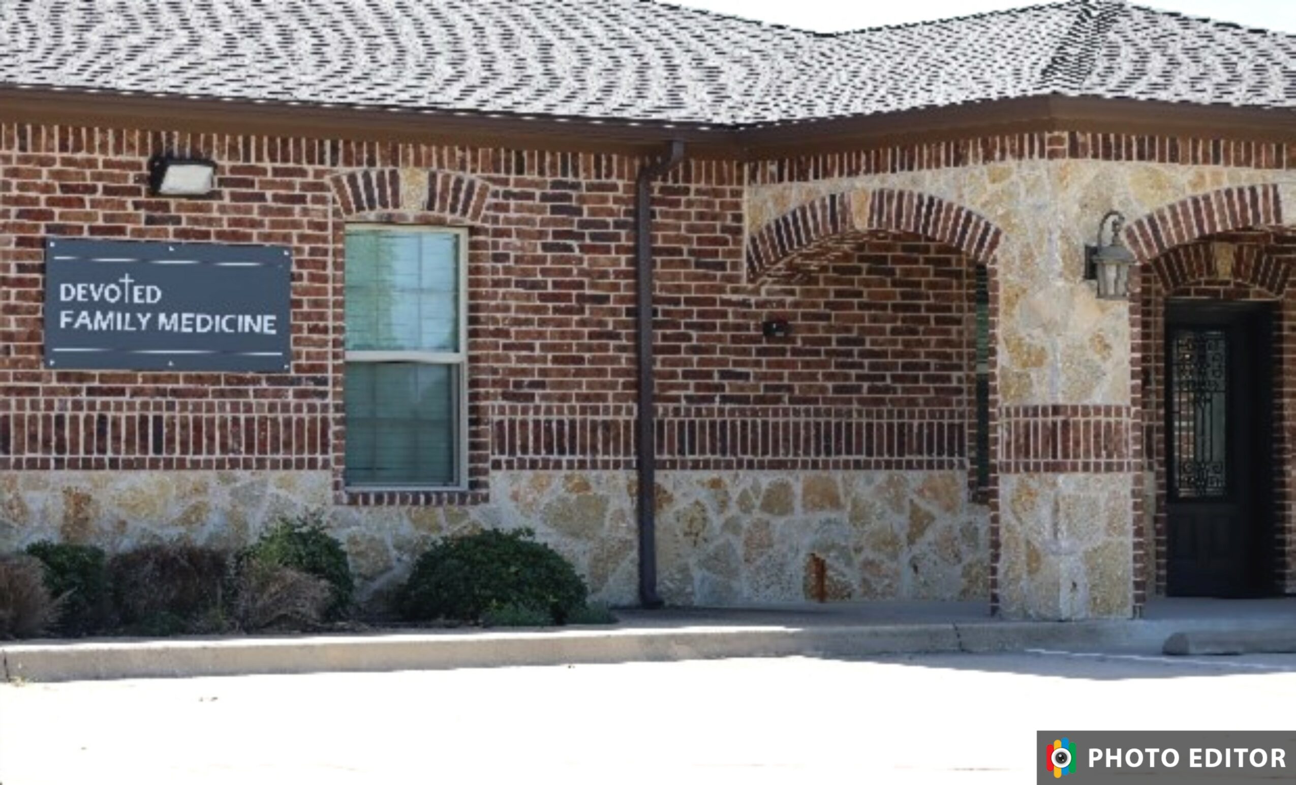 Brick building with a sign that reads 'Devoted Family Medicine,' window, and stone archway entrance.