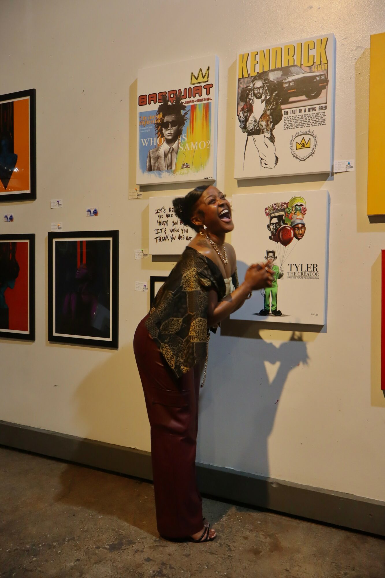Person laughing and holding a drink, standing in front of colorful comic book covers on a wall.