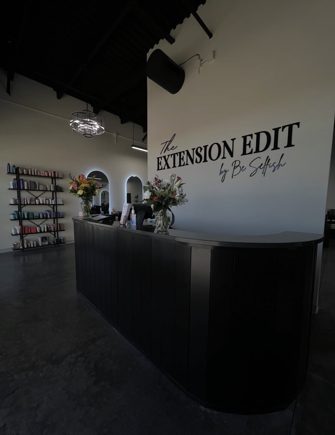 Interior of a room with a curved reception desk, floral arrangements, and a wall with text reading 'Extension Edit by B. Scott'.