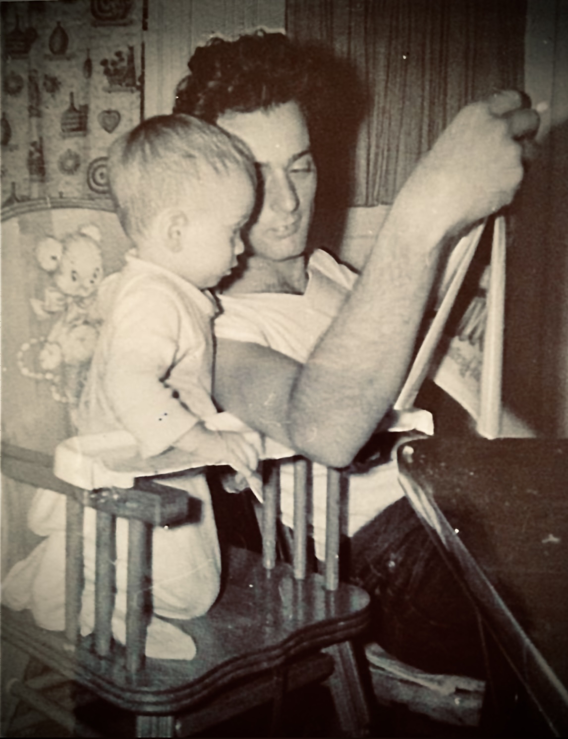 Adult and child looking at a framed picture together, with toys in the background.