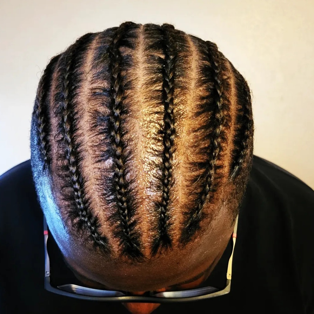 Top view of a person's head with neatly braided hair, showing multiple cornrows styled close to the scalp.