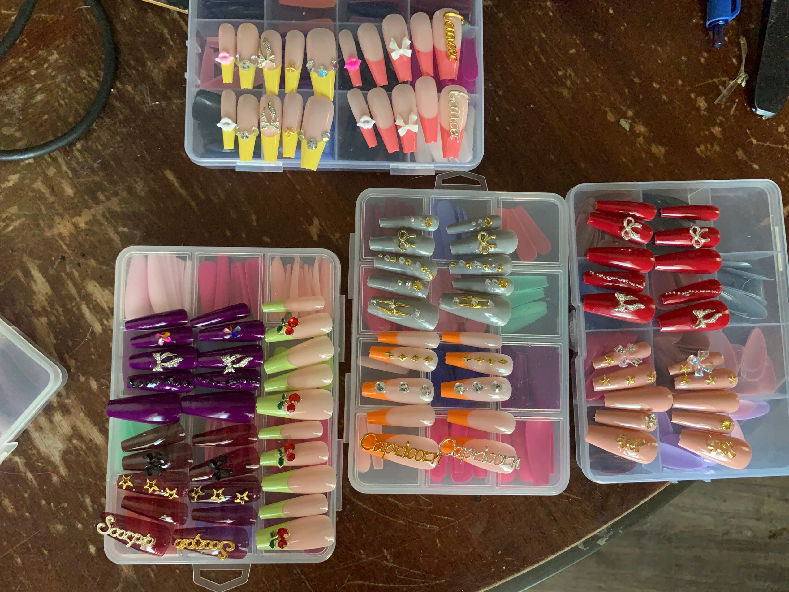 Three plastic cases with colorful hair clips on a wooden surface, with a small box of additional clips above.