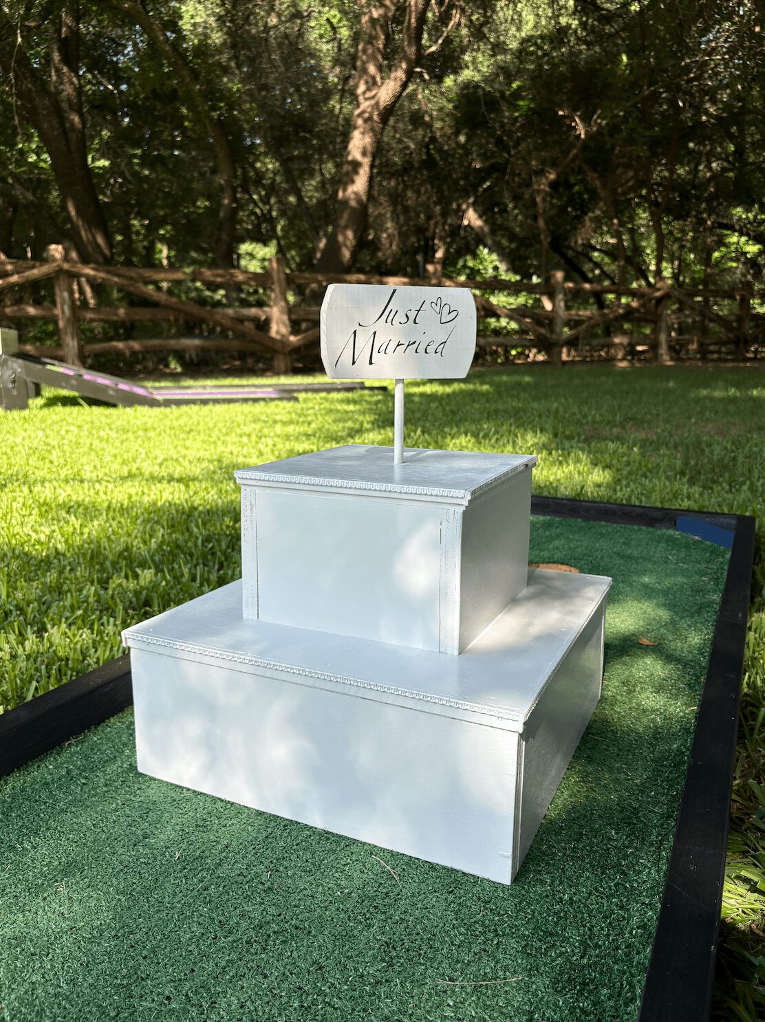 Two white boxes on a green surface outdoors, with a sign reading