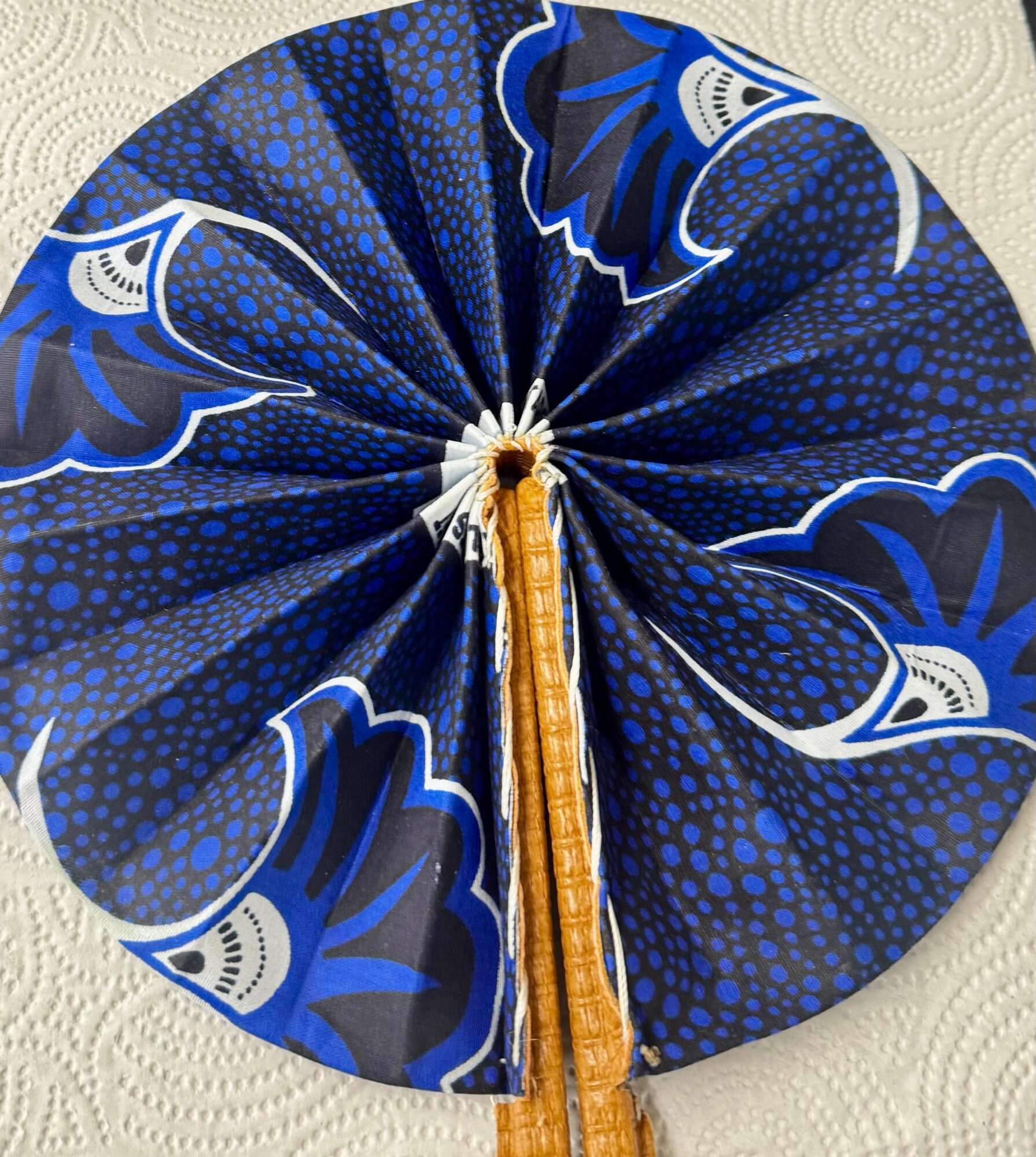 Folded blue fabric with floral patterns, gathered in a circular shape with a central white and gold element.