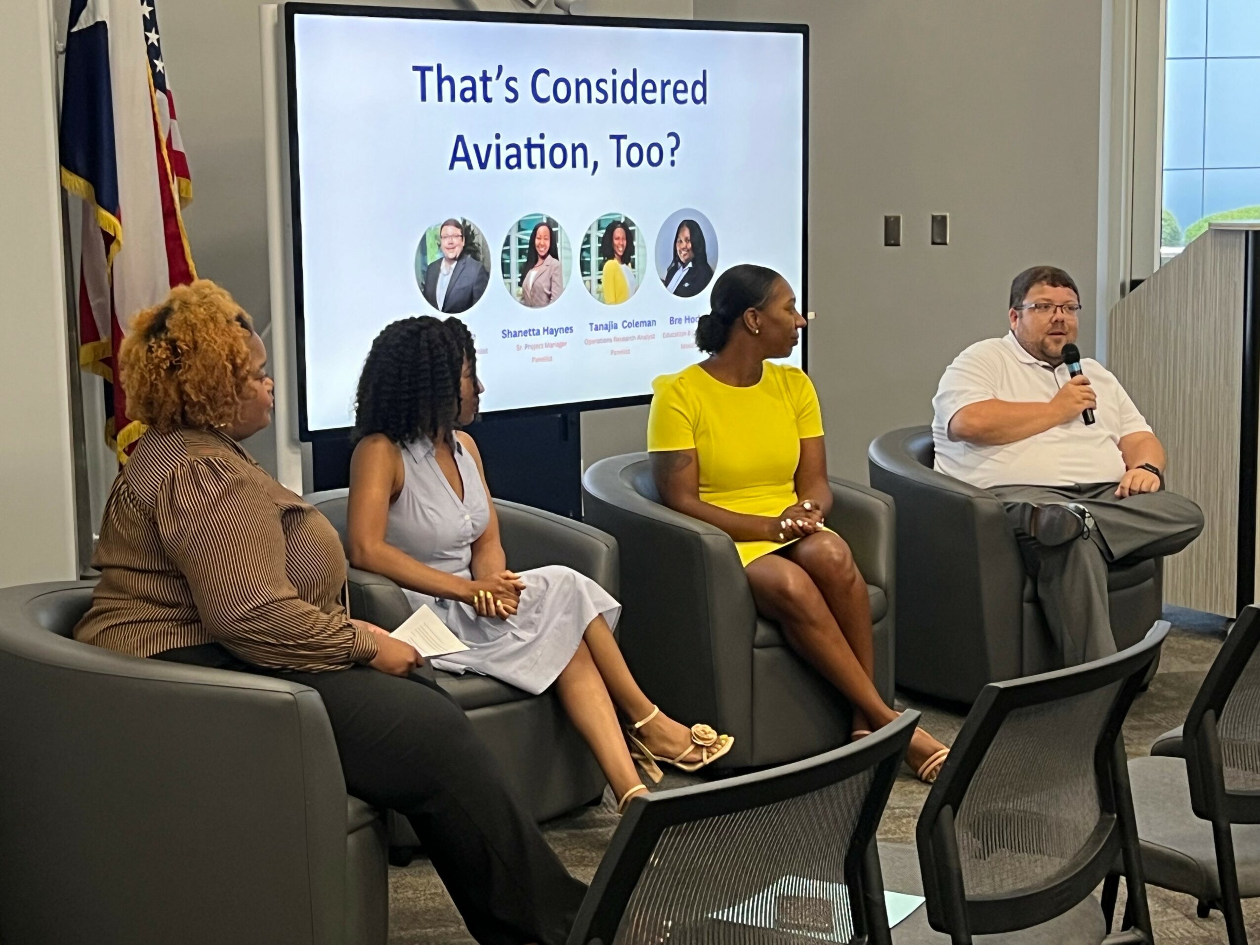 Four people seated in a panel discussion, with a screen behind them displaying the text 'That's Considered Aviation, Too?' and images of four individuals.