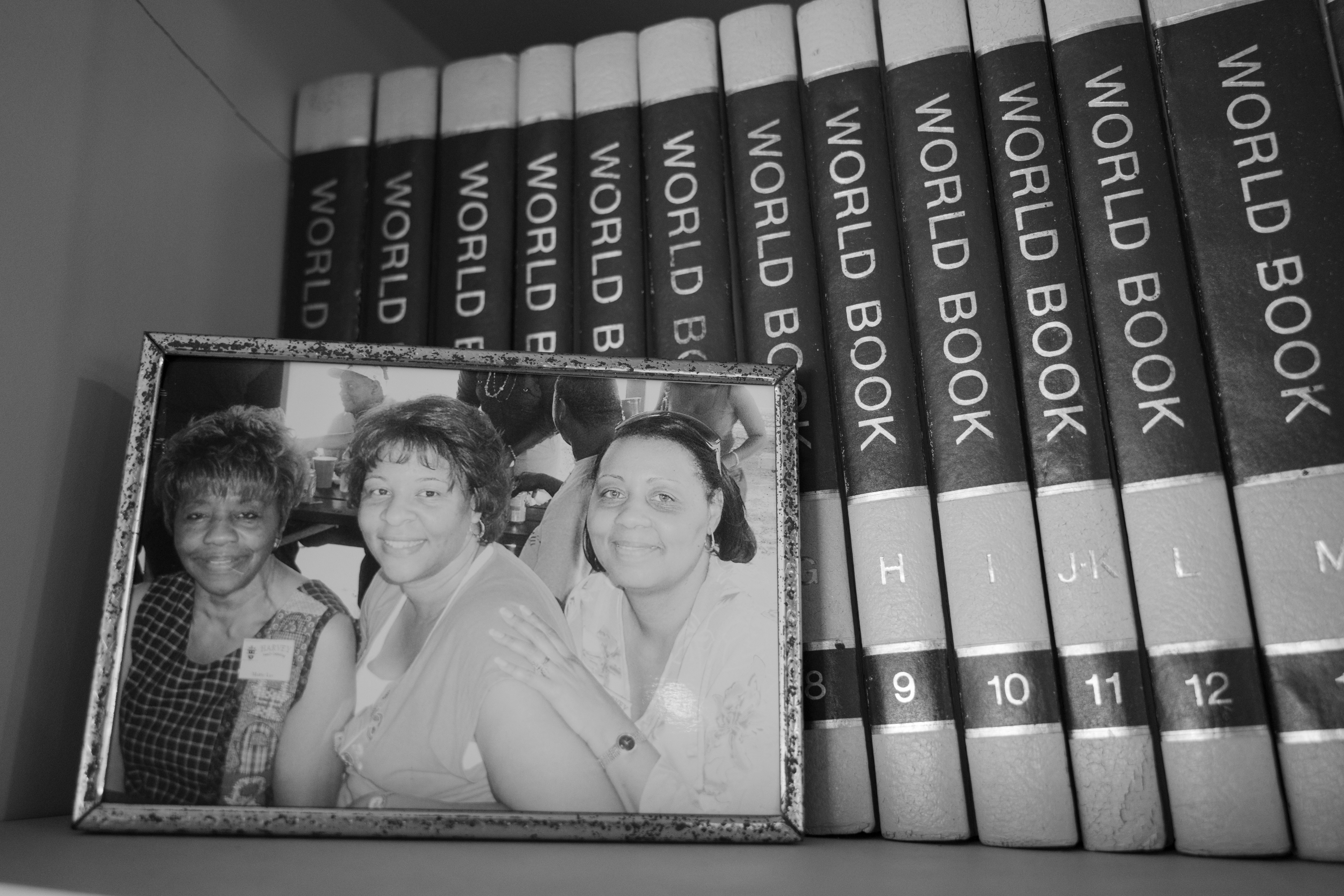 Black and white photo of three people, with books labeled 'WORLD BOOK' in the background.