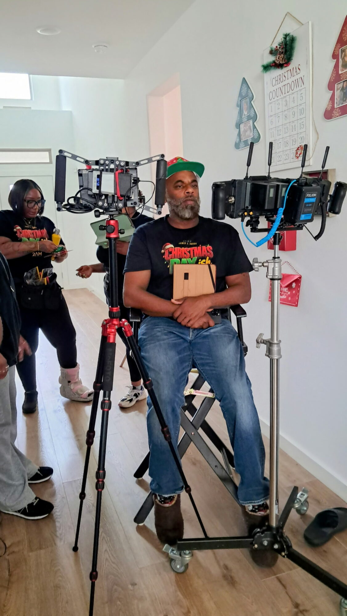 Person sitting on a motion capture device with cameras and sensors, in a room with holiday decorations on the wall.
