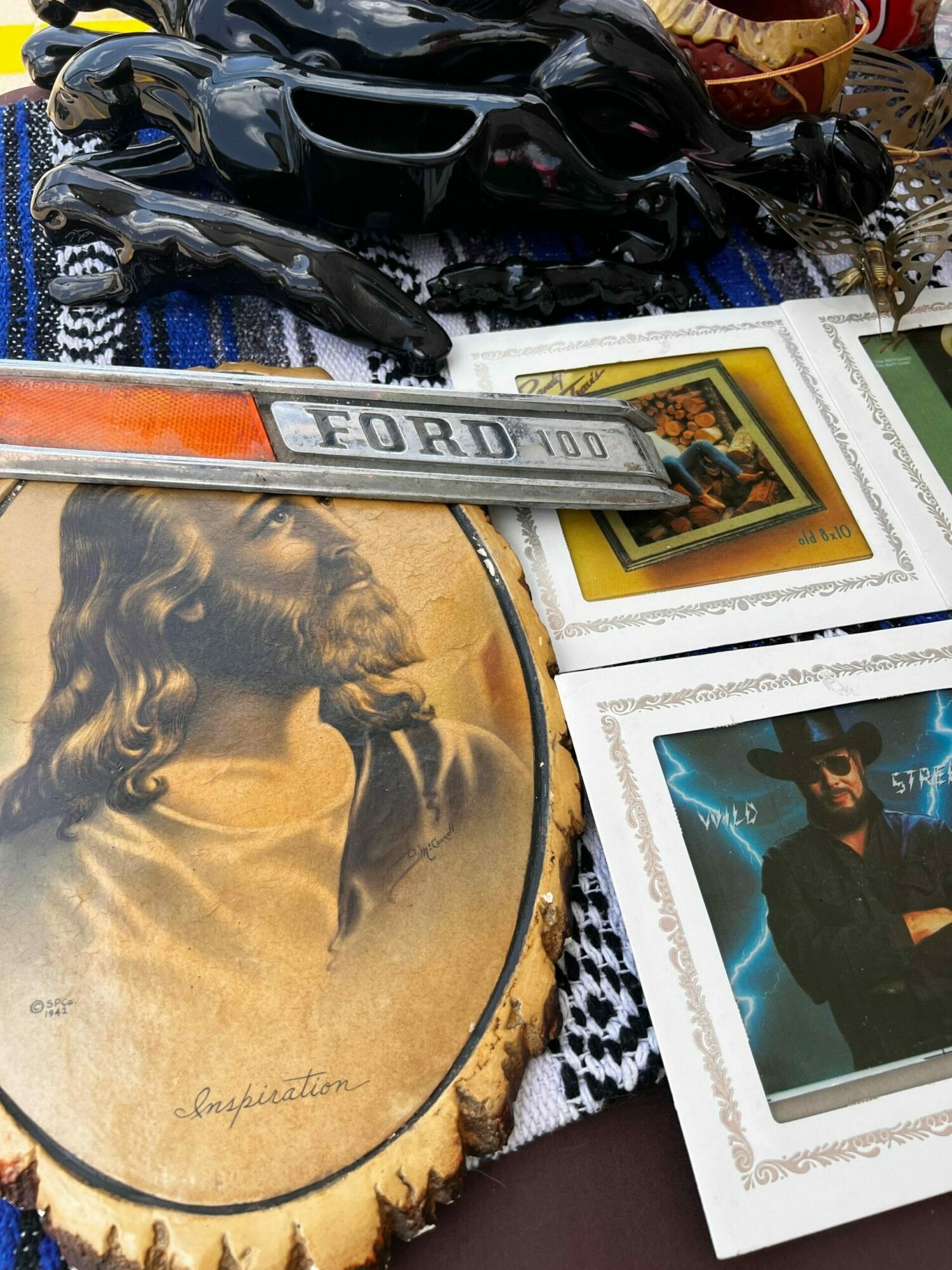Open book with images and a ruler, surrounded by various objects including a black item and photographs.