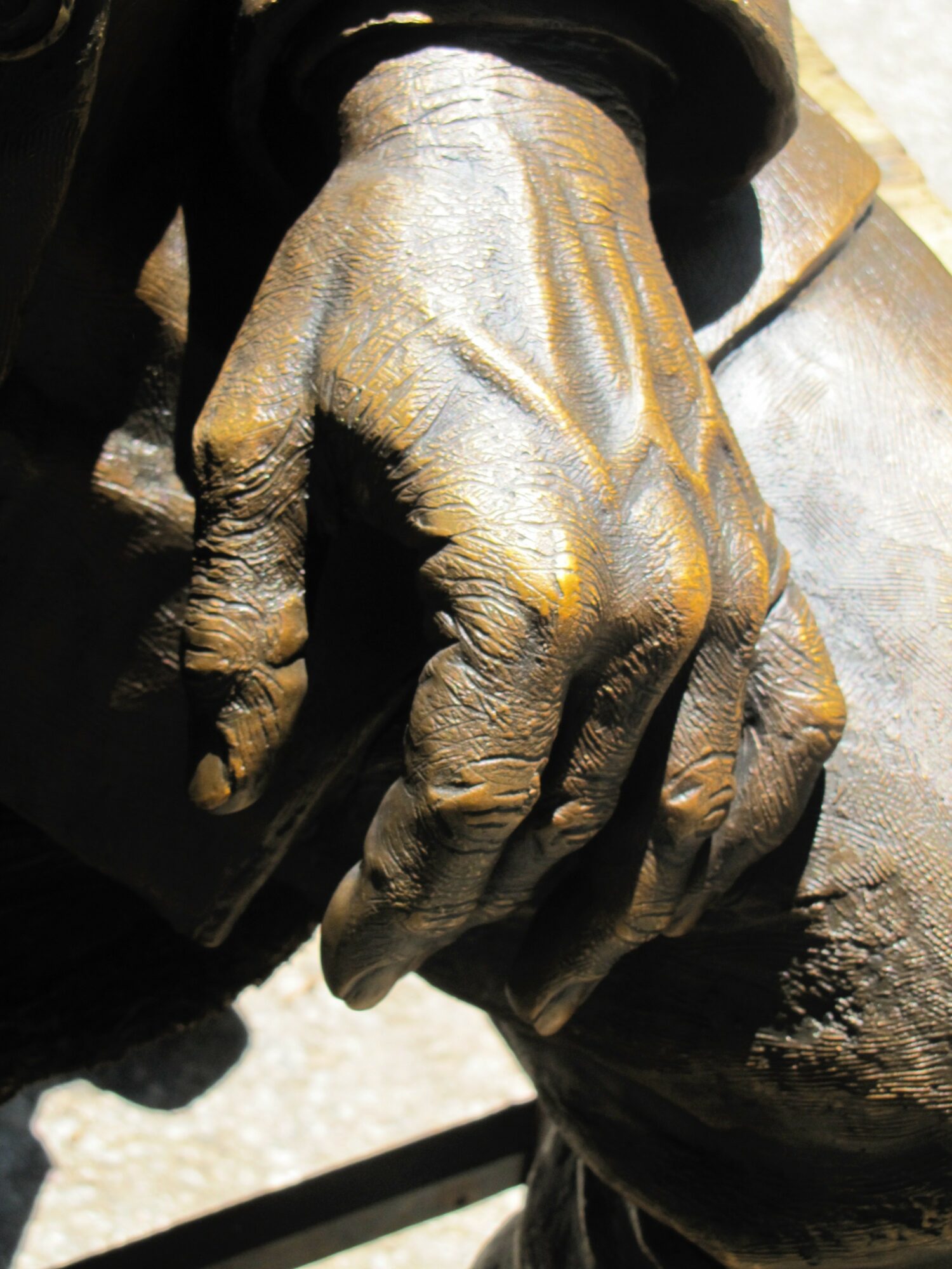Close-up of a weathered, textured hand resting on a surface, with visible wrinkles and aged skin.