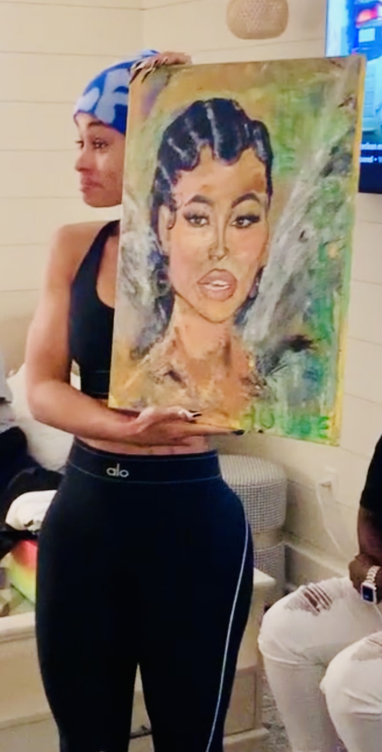 Person holding a colorful portrait painting of a woman with braided hair and makeup.