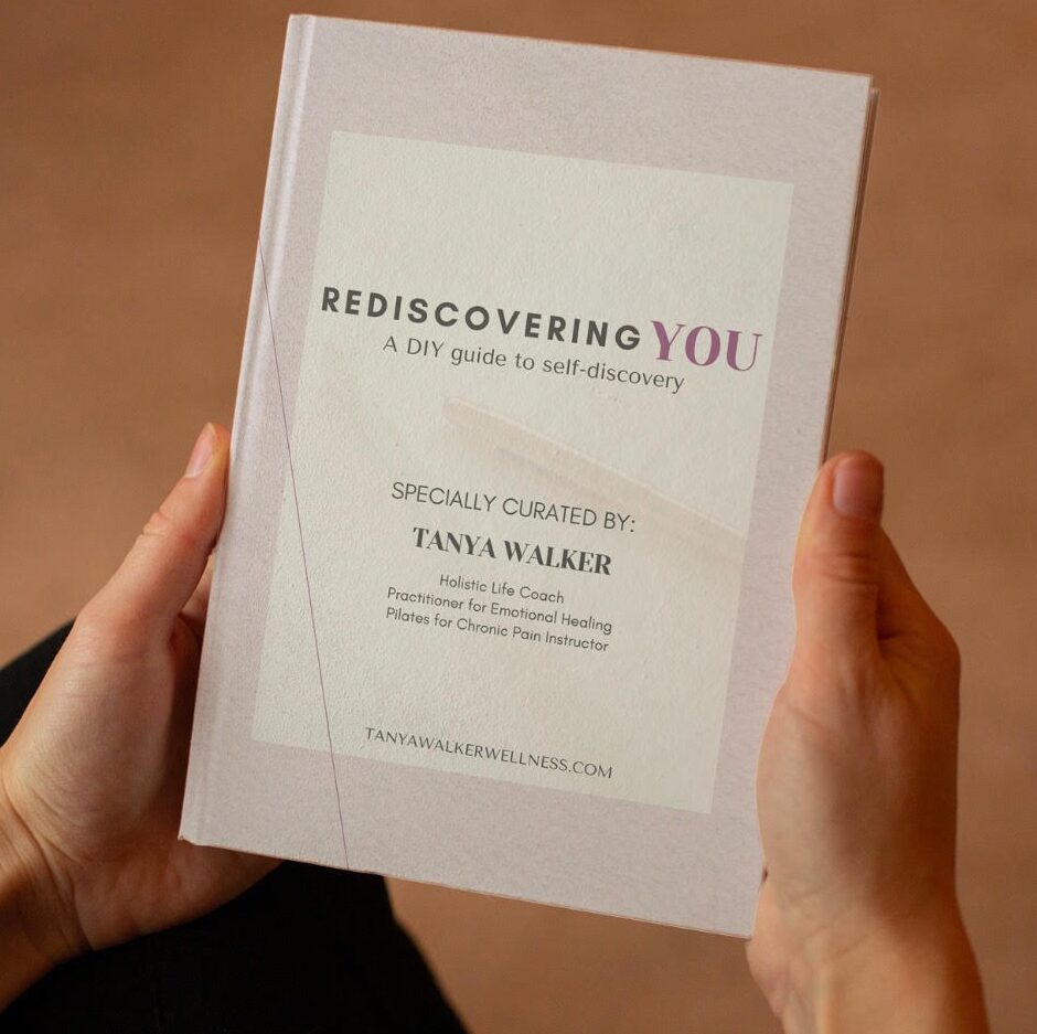 Person holding a book titled 'Rediscovering You' with a white cover and black and purple text.
