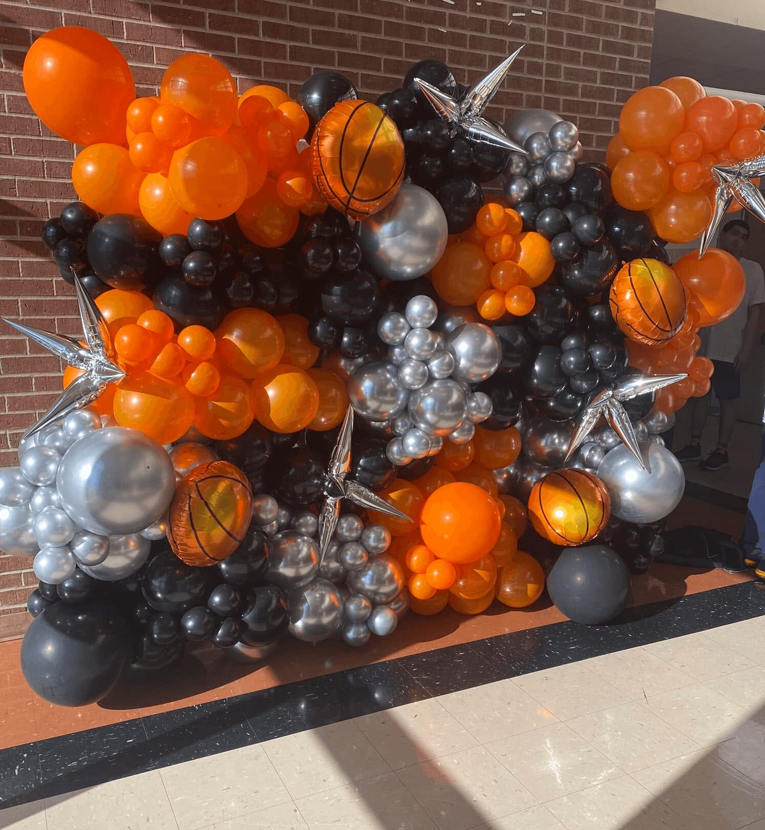 Balloon display with orange, black, silver, and star-shaped balloons arranged in a decorative cluster.