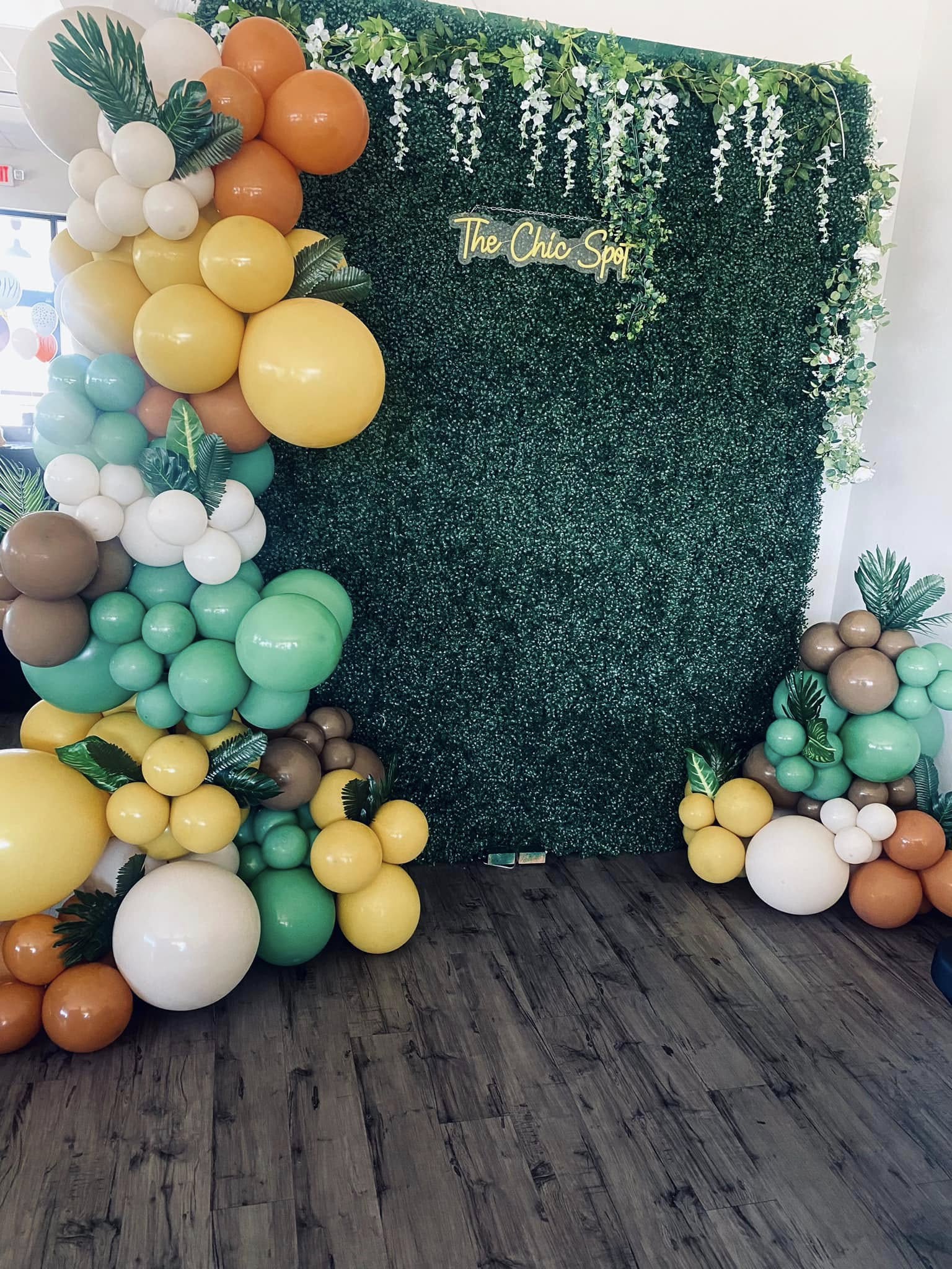 Decorative green hedge backdrop with colorful balloons on the left and right sides, and a sign reading 'The Ohio Spa' in gold lettering.