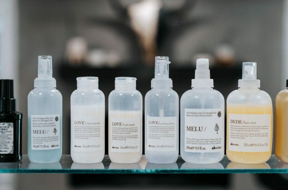 Several bottles of skincare products on a glass surface with a blurred background.