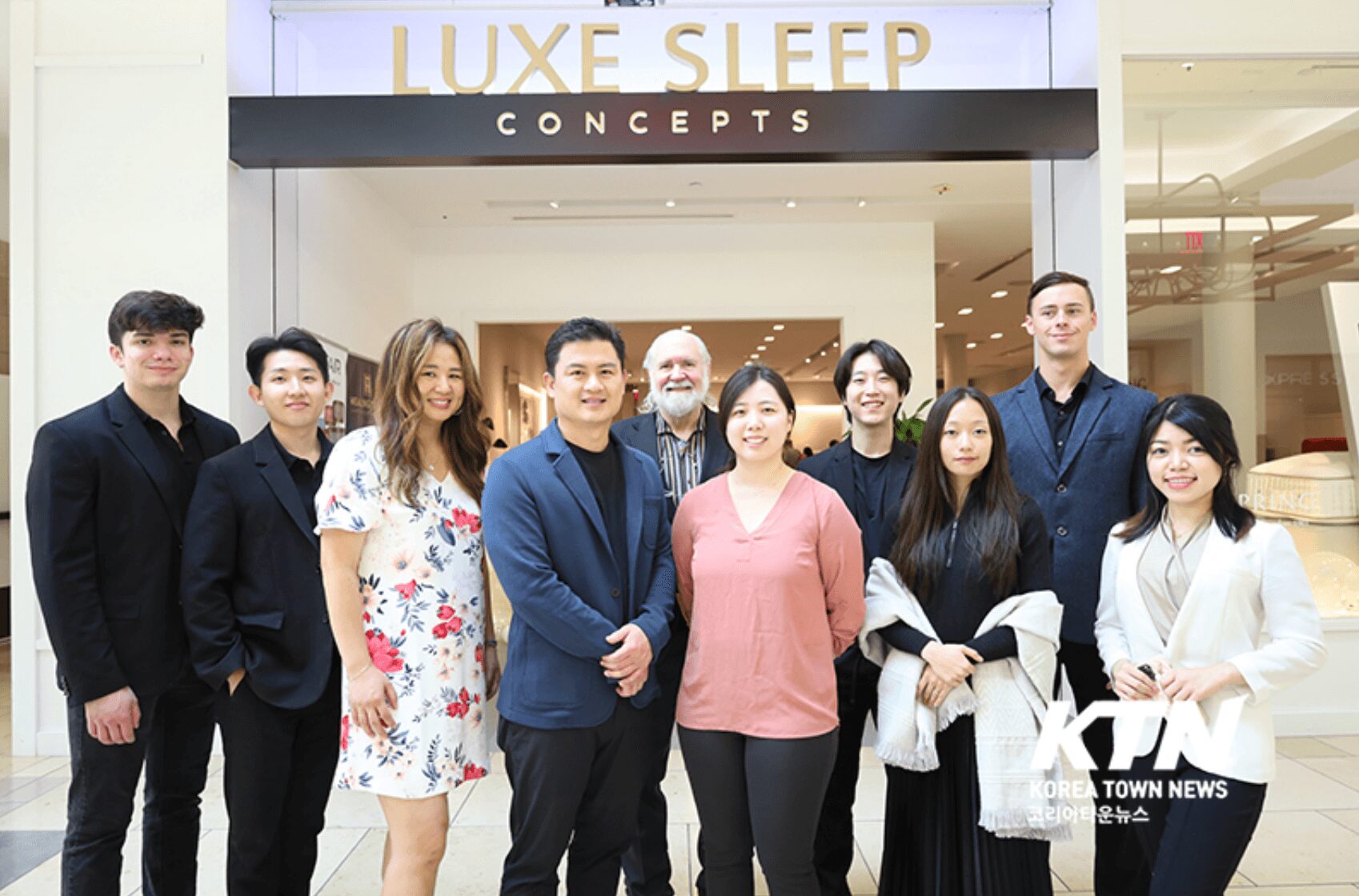 Group of ten people standing in front of a store named LUXE SLEEP CONCEPTS inside a shopping mall.