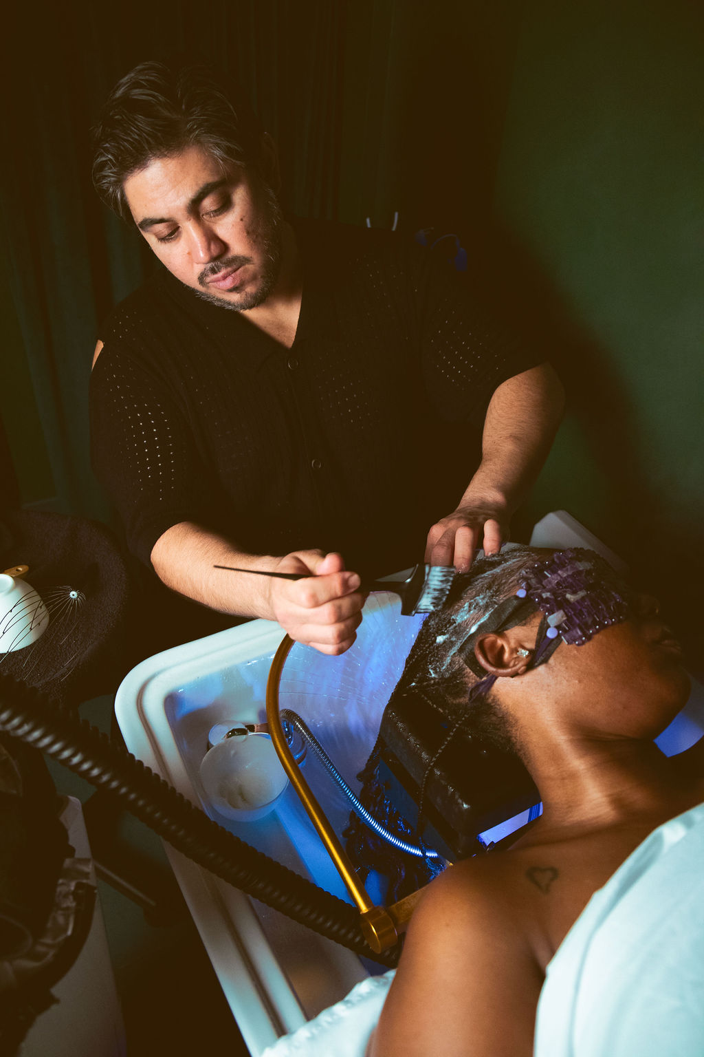 Person performing a medical procedure on a patient in a clinical setting, with medical equipment visible.