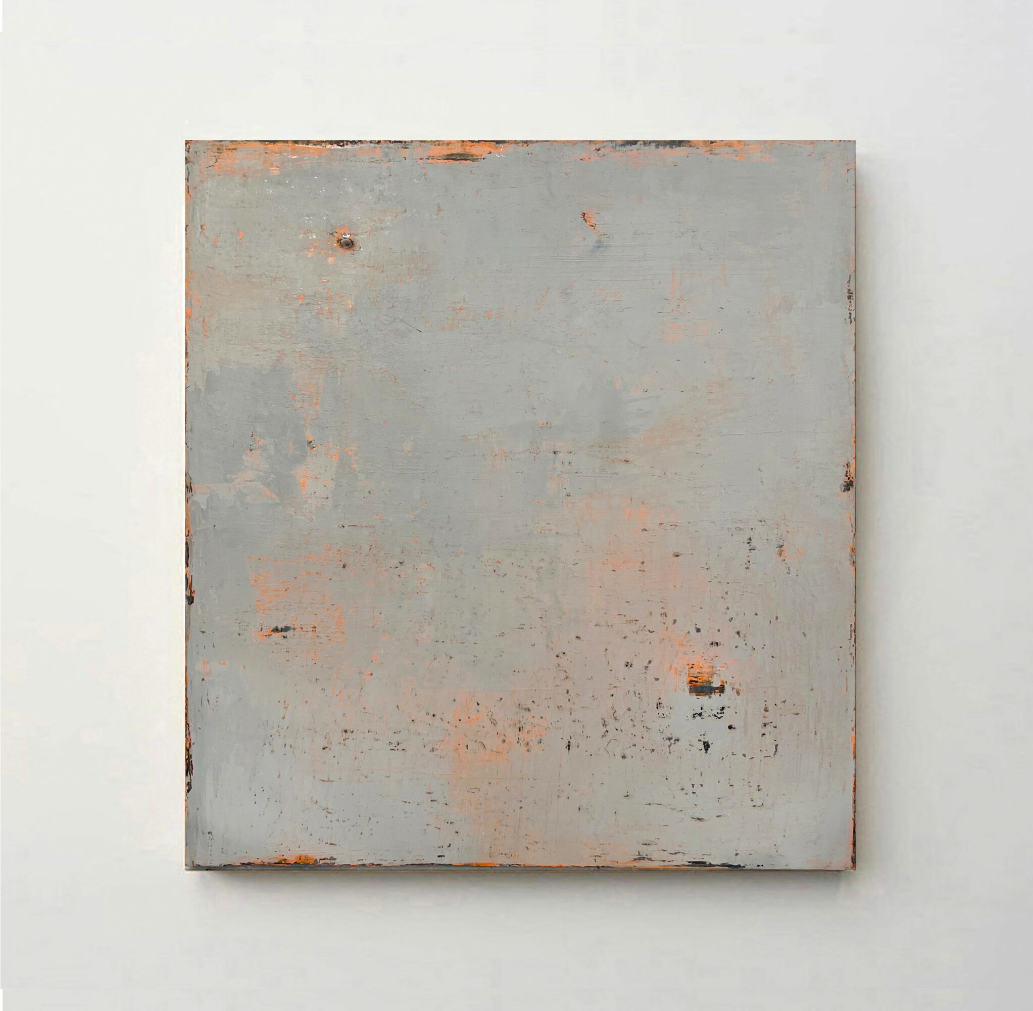 A square, textured, light gray painting with rust-colored spots, mounted on a white wall.