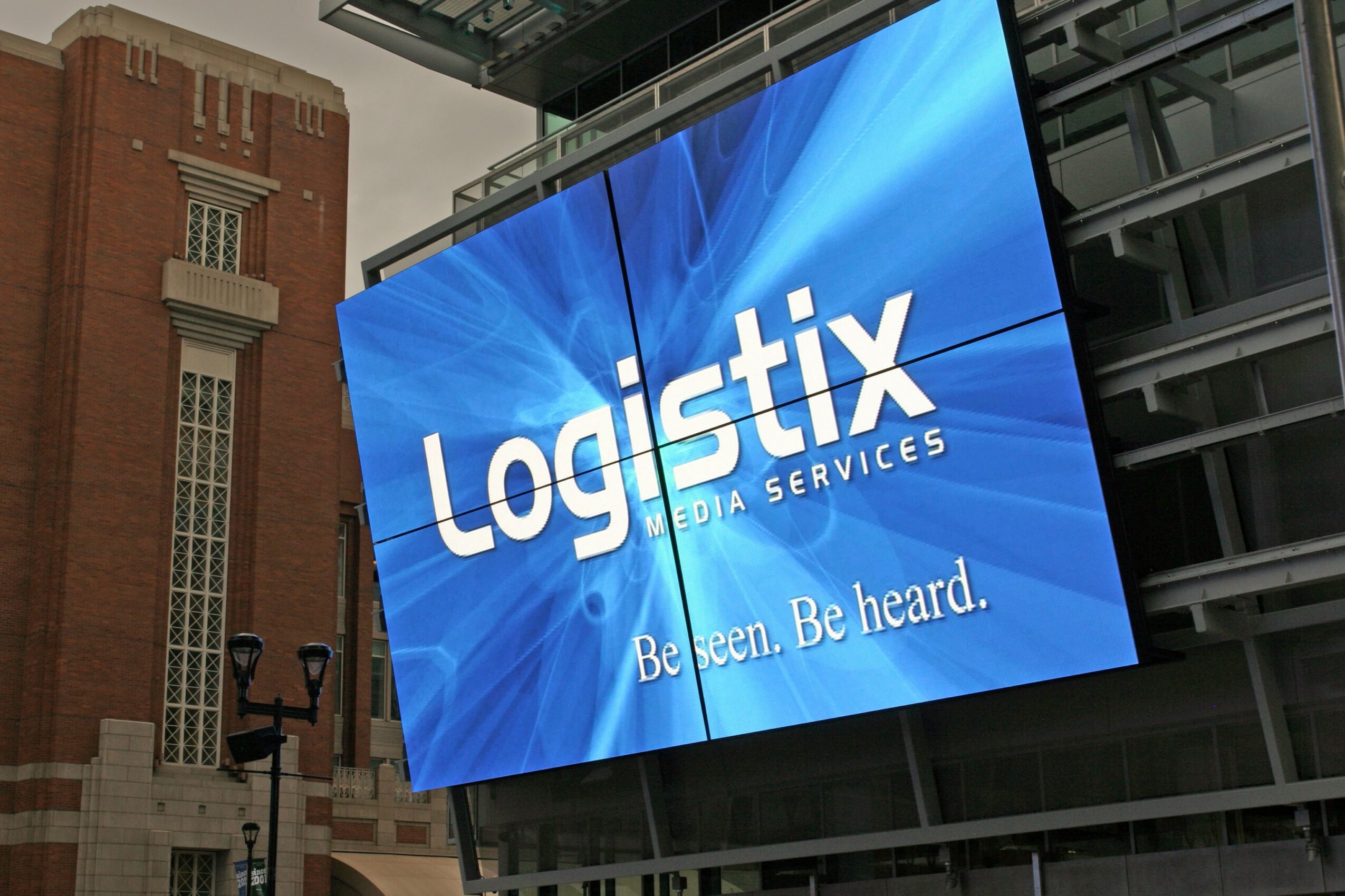 Large digital screen displays 'Logistix Media Services' with the tagline 'Been. Be heard.'