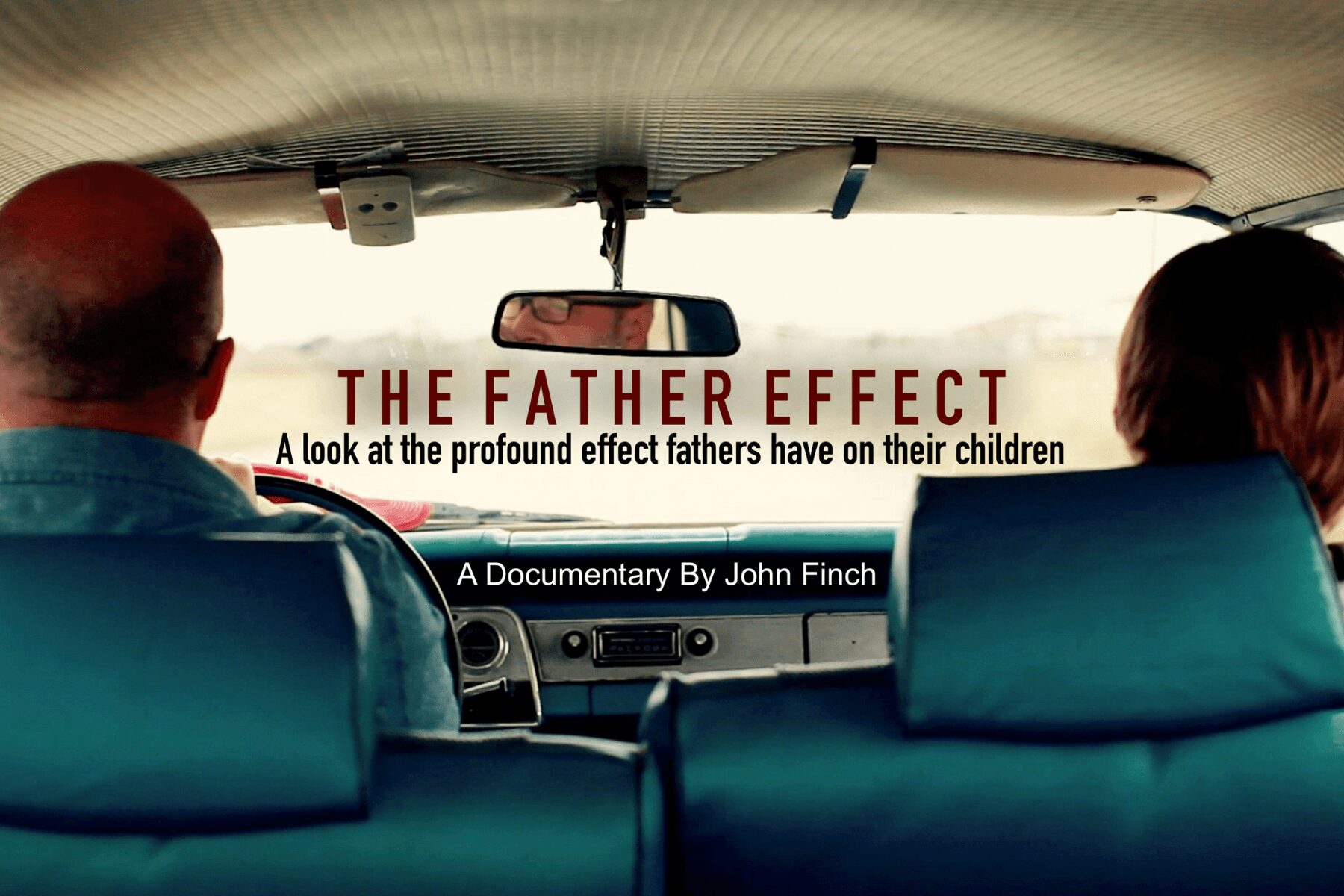 View from the back seat of a car showing two adults in front, with a documentary title about fathers on the screen.