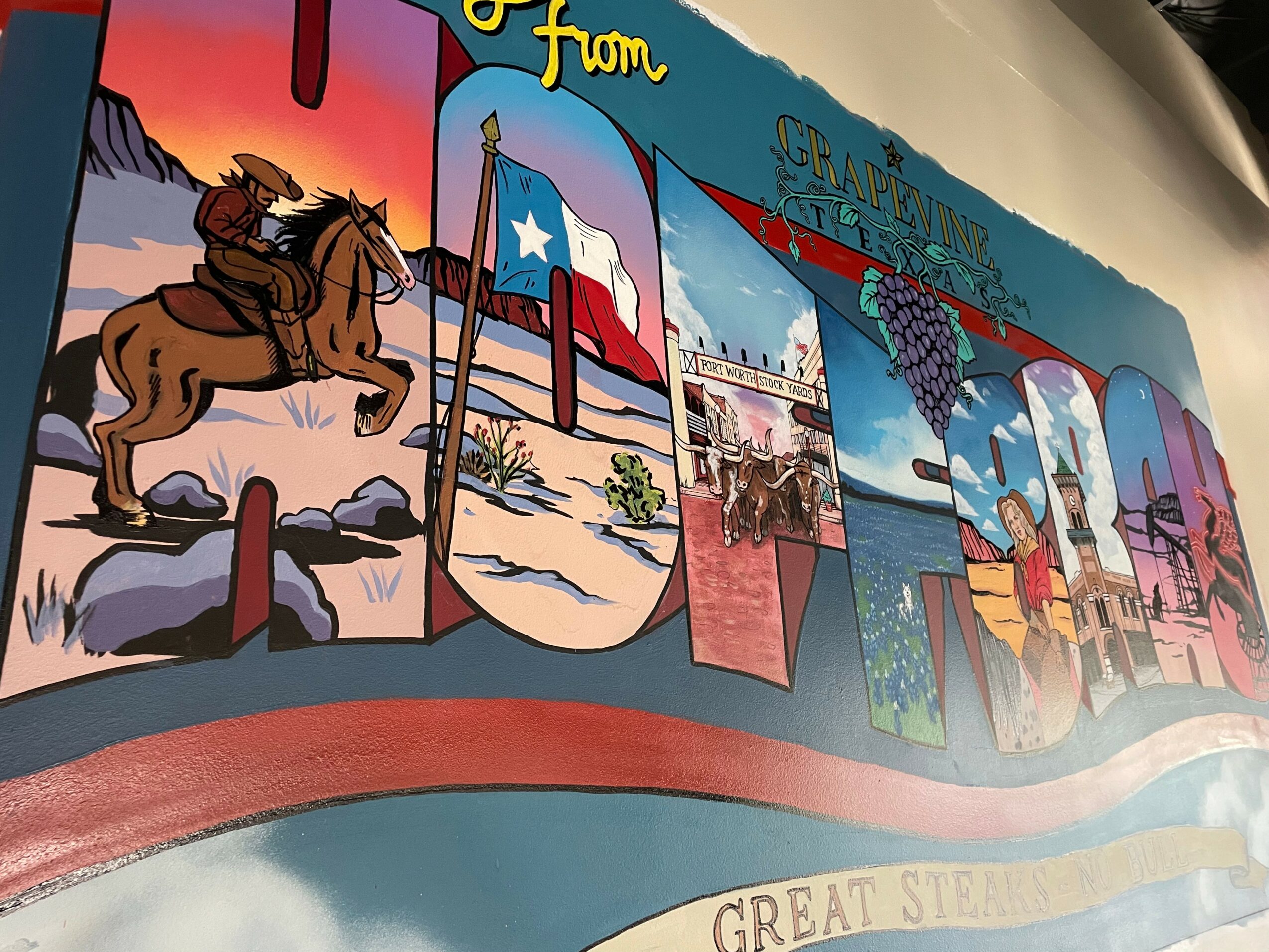Colorful mural with Texas flags, a cowboy on a horse, and cityscape elements, celebrating Texas and the Great Steamboat Race.