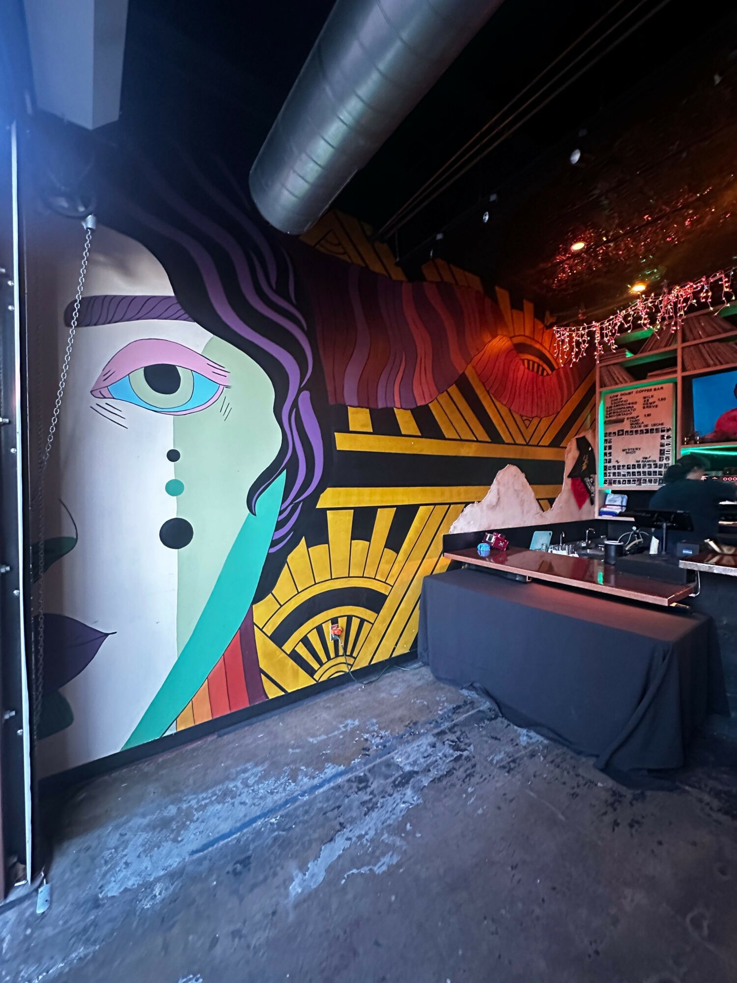 Colorful street art mural with abstract face and geometric patterns on a wall at night.
