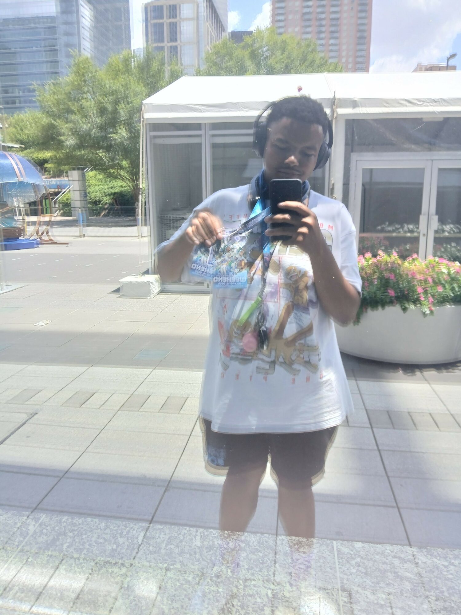 Person in a white dress holding a bouquet of flowers, taking a selfie outdoors on a sunny day.