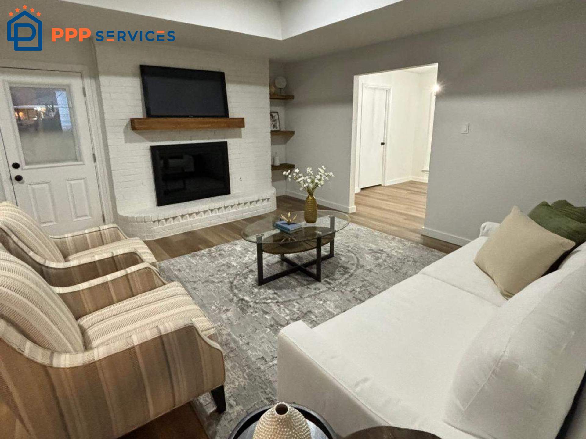 Living room with fireplace, TV, striped armchairs, white sofa, coffee table, and decorative items, bright and cozy space.