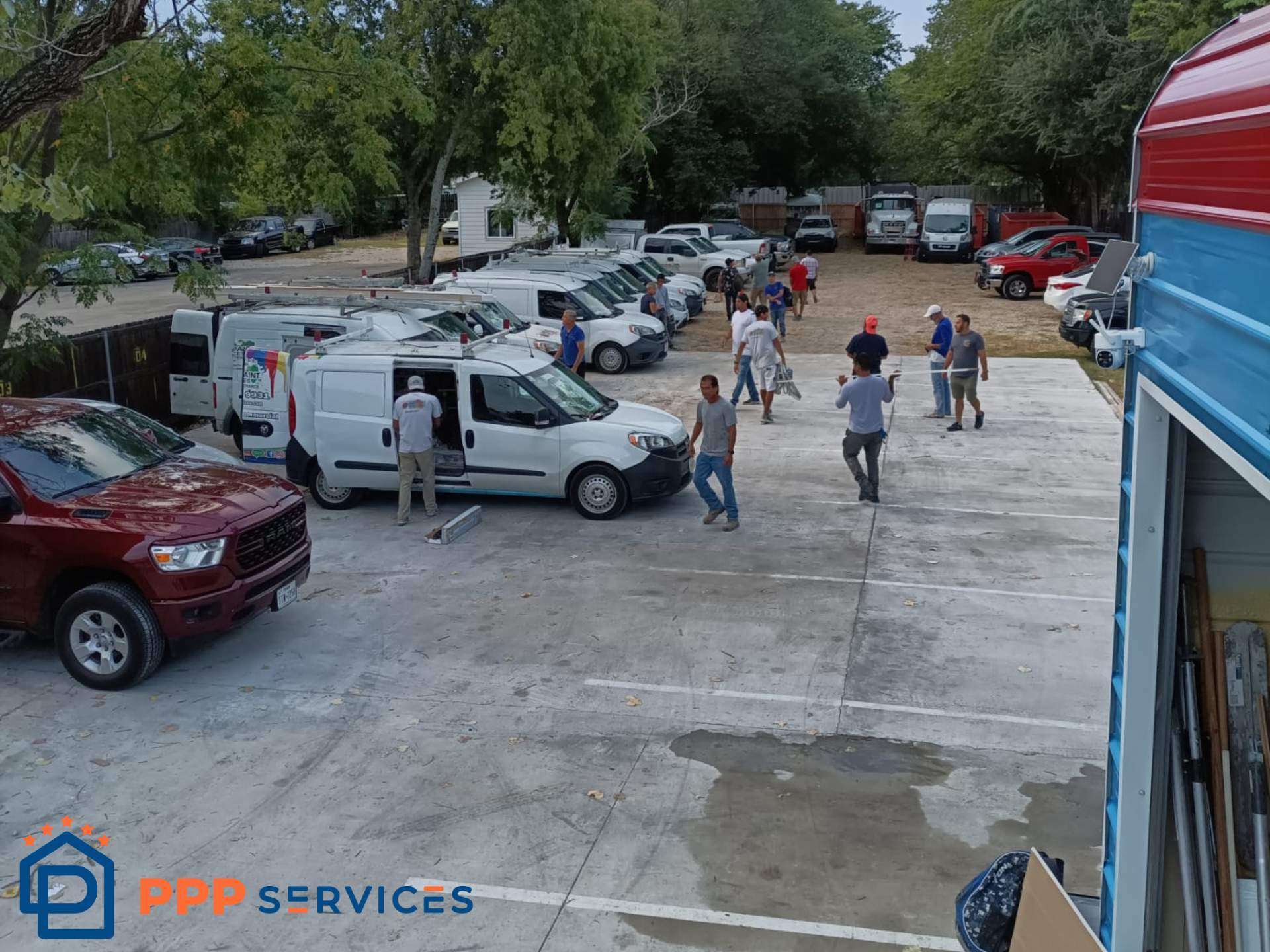 People walking in a parking lot with vehicles and trees in the background, some vehicles parked and others moving.