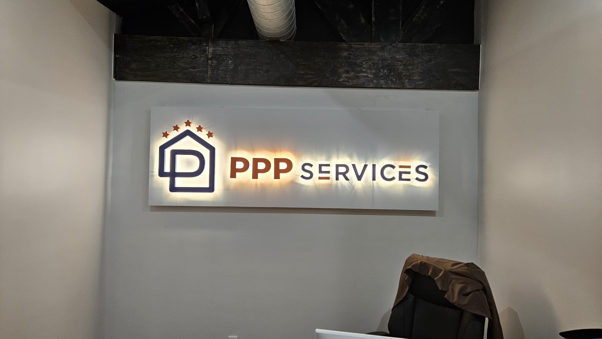 Signboard with house icon and text 'PPP SERVICES' on a wall.