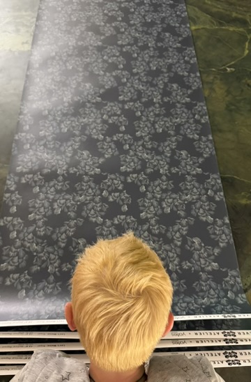 Top view of a person with blonde hair looking at a patterned surface, possibly a table or floor, with floral design.