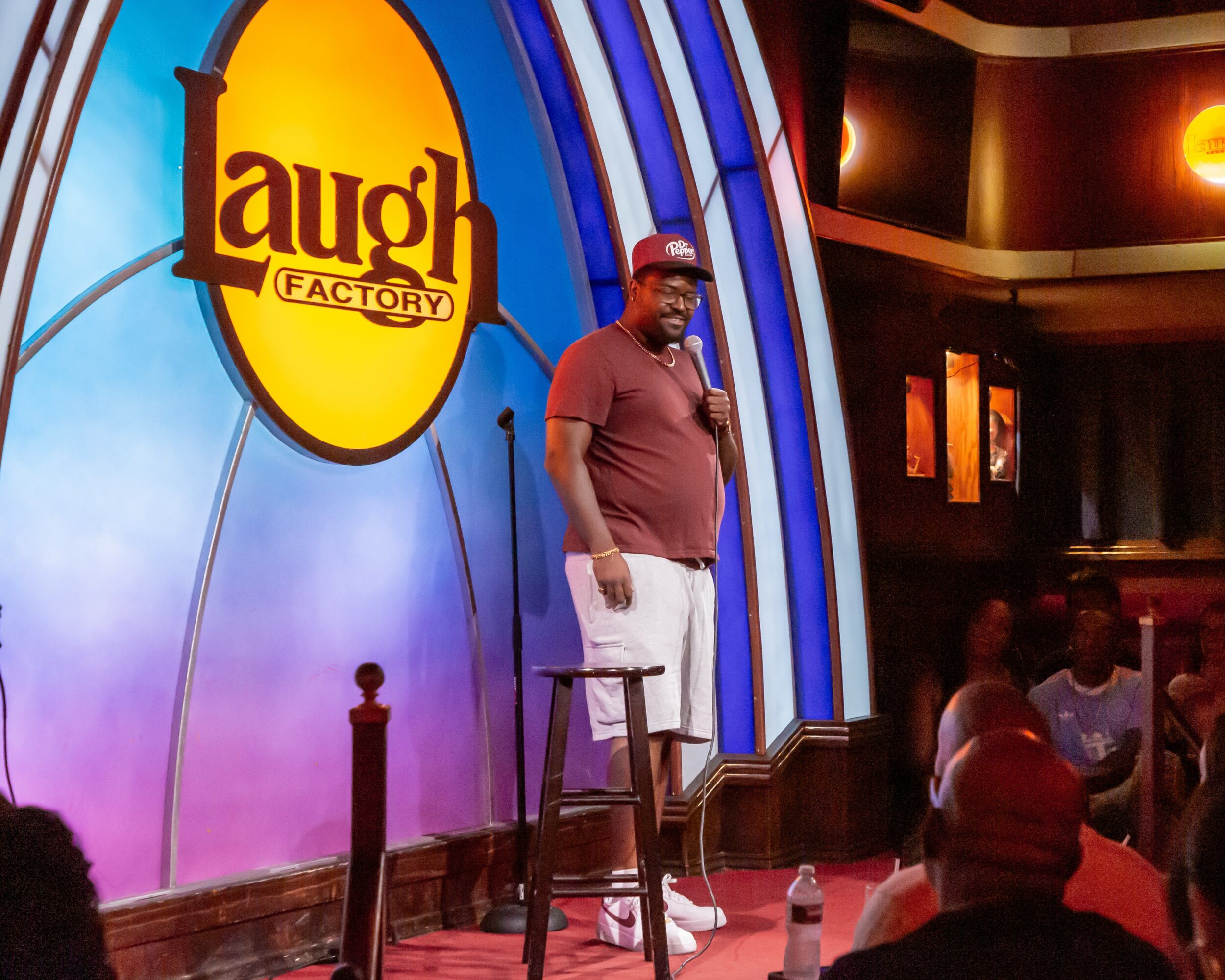 Comedian on stage at Laugh Factory comedy club, with audience in background.