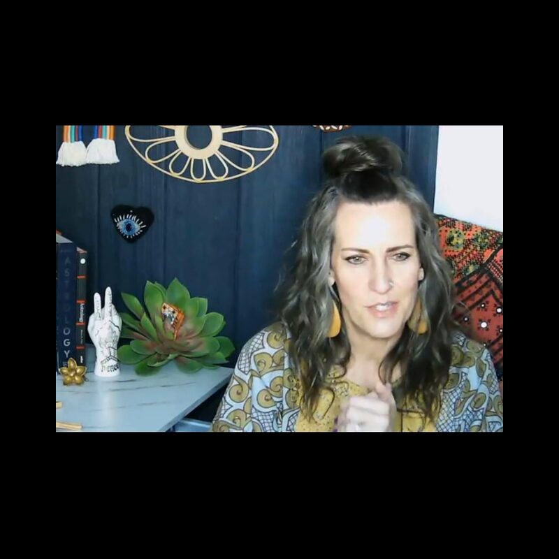 Woman with long wavy hair and a top knot, wearing patterned clothing, in a room with decorative items and artwork.
