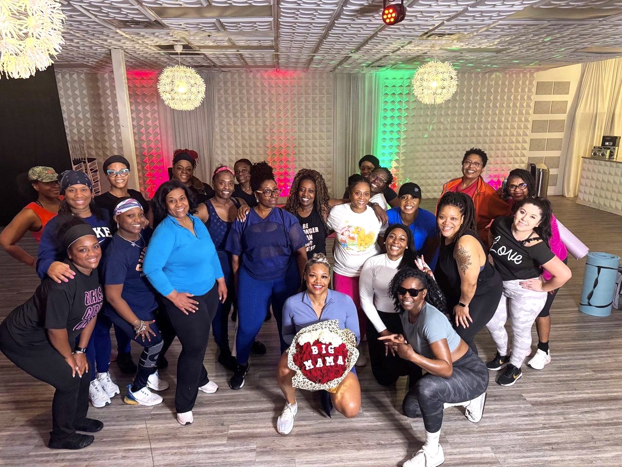 Group of people posing indoors with colorful lighting and decorations, some smiling and making gestures, in a festive setting.