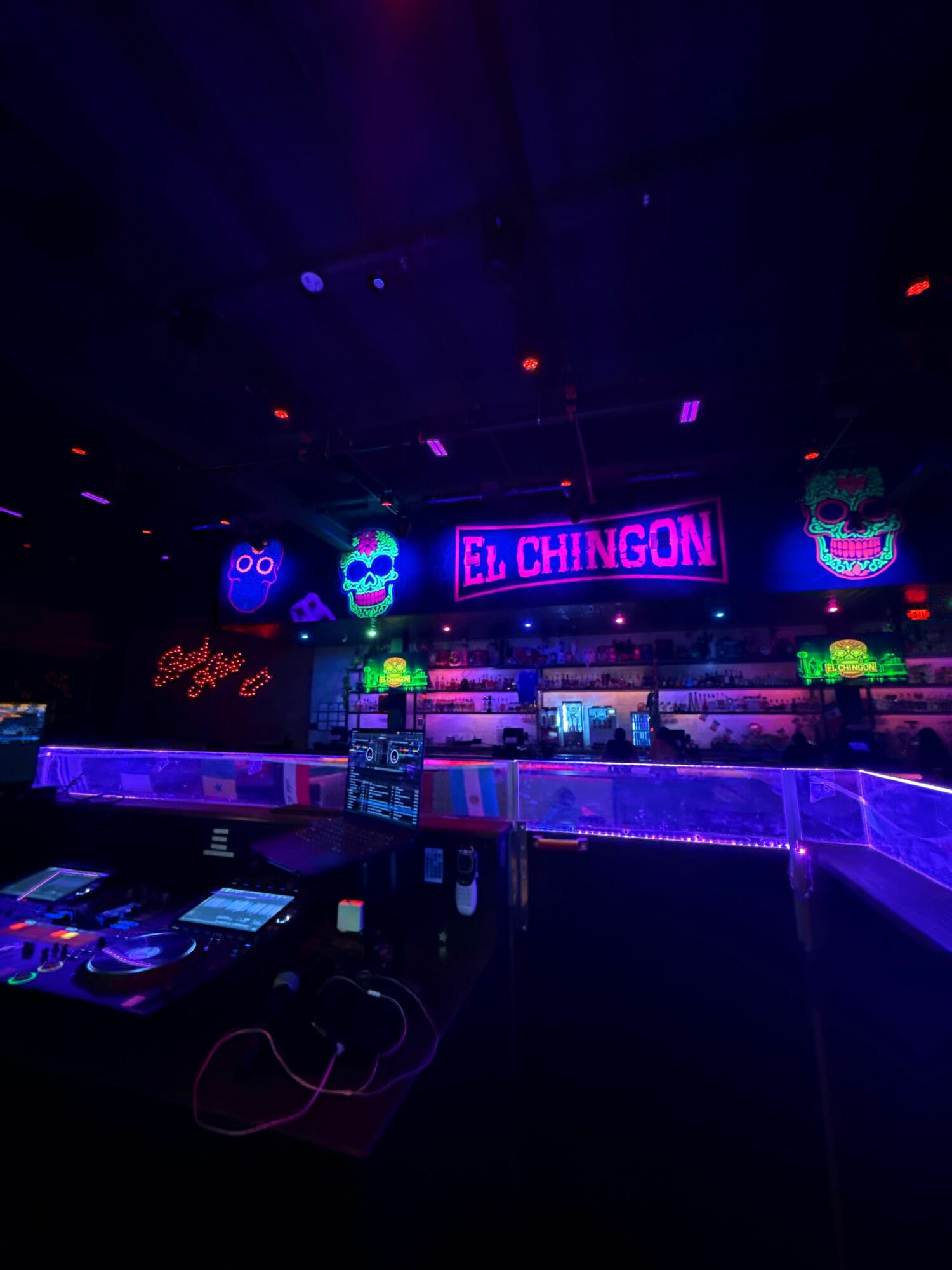 Nightclub scene with neon signs, DJ equipment, and colorful lighting effects.