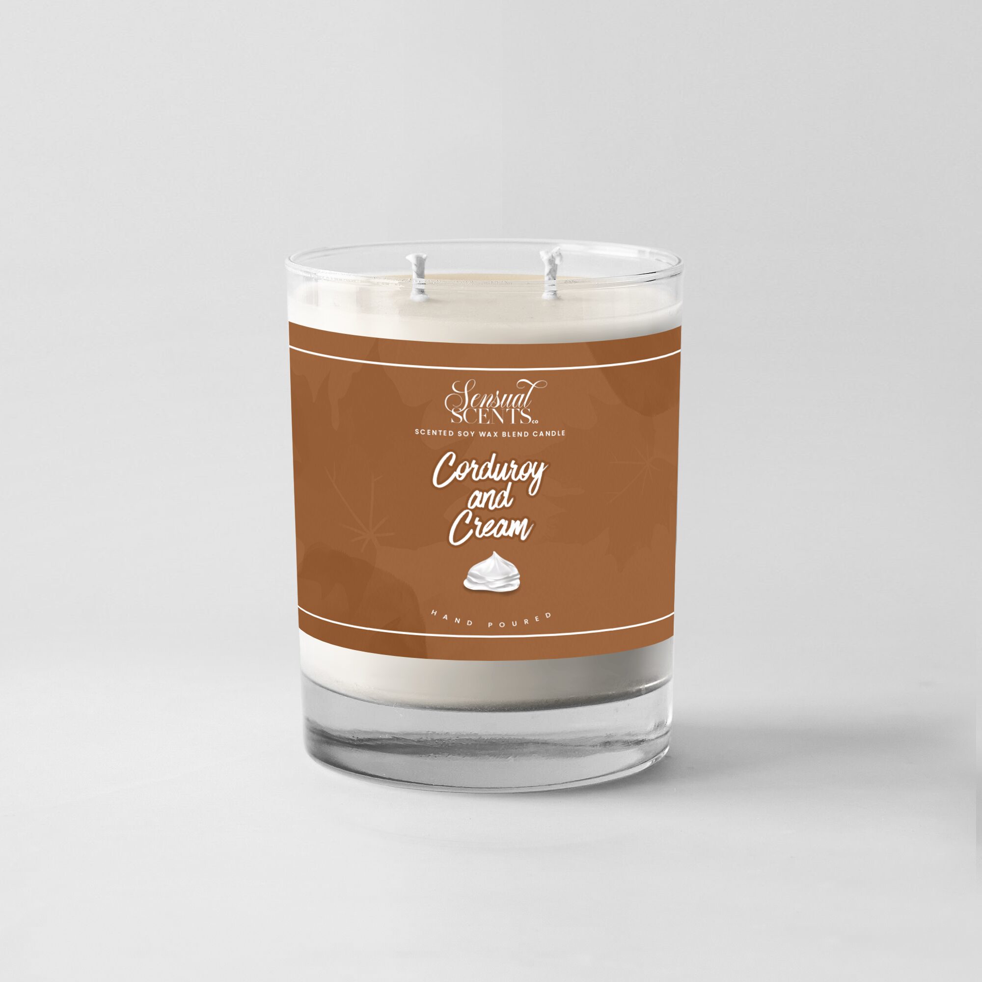 A candle in a glass jar with a brown label reading 'Coconut and Cream' and a white wax interior.