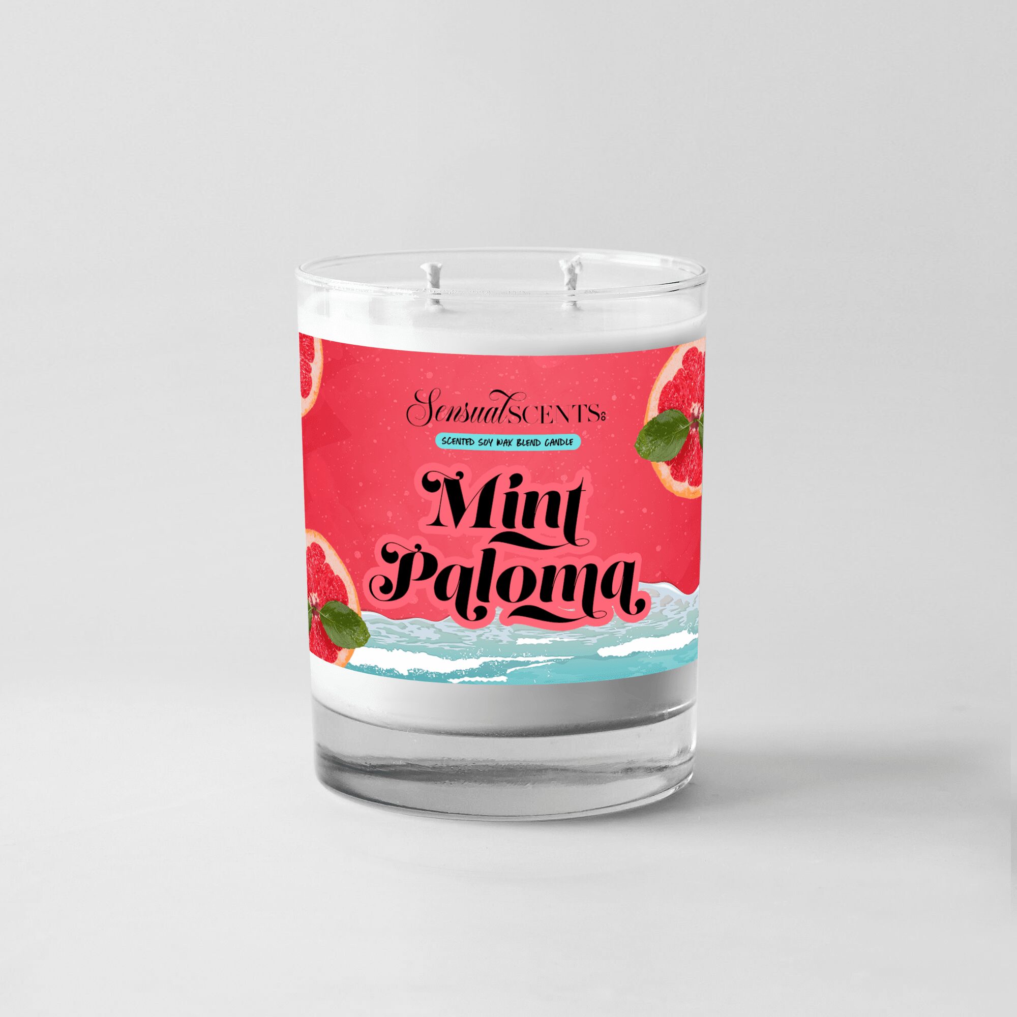 A candle in a glass container with a pink label reading 'Mint Paloma' and illustrations of mint leaves and strawberries.