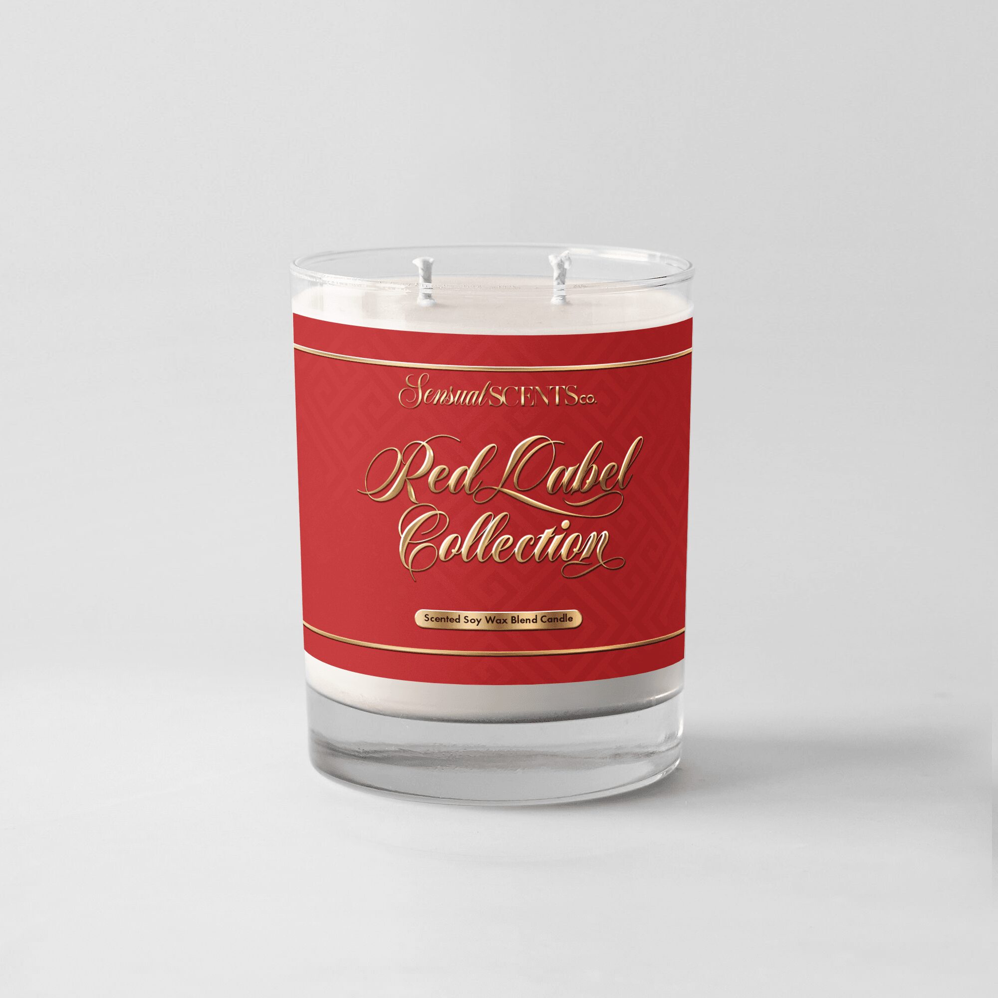 Red label collection candle in a clear glass container with white wax, on a plain light background.