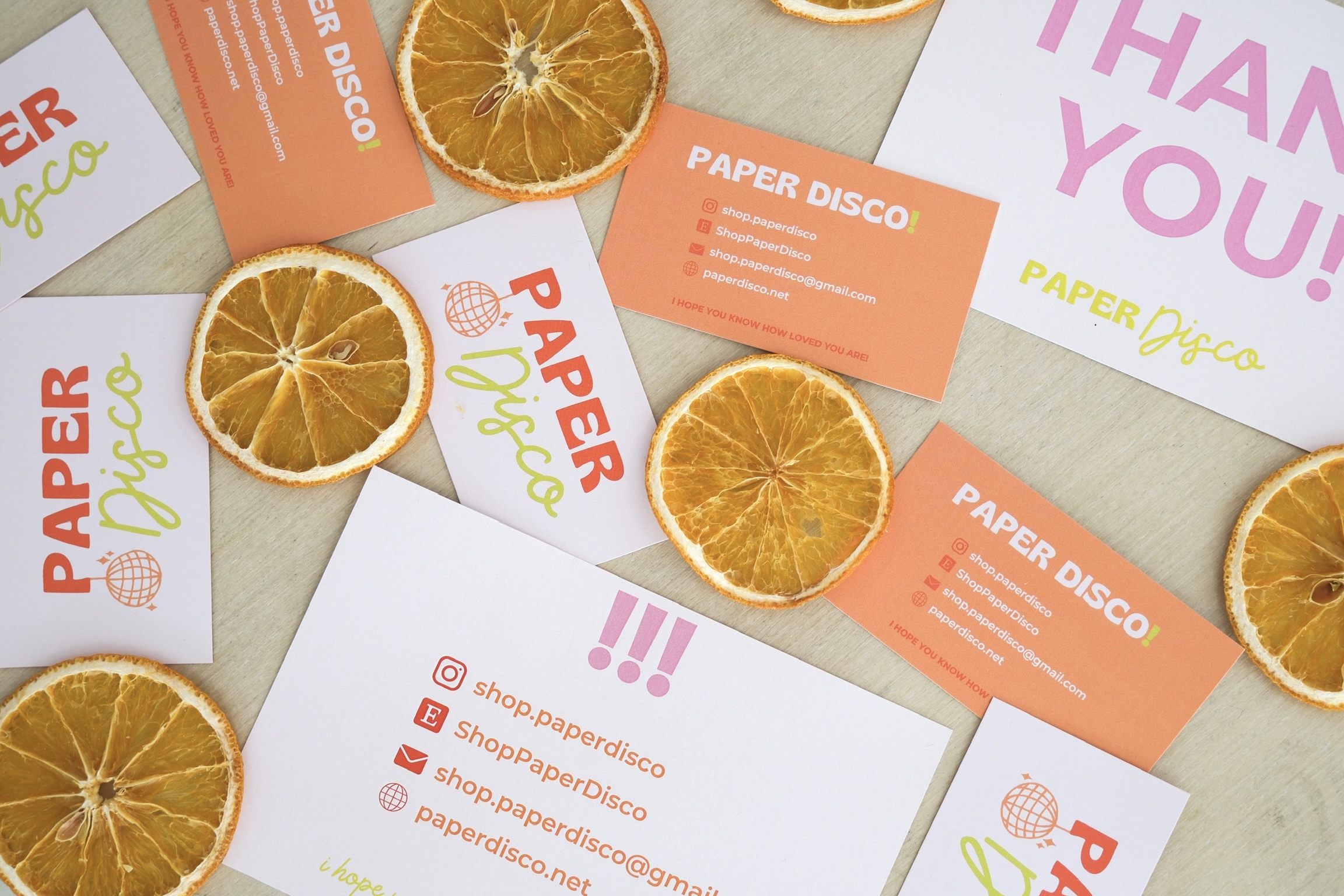 Dried orange slices and paper disco flyers scattered on a light surface, with colorful text and logos.