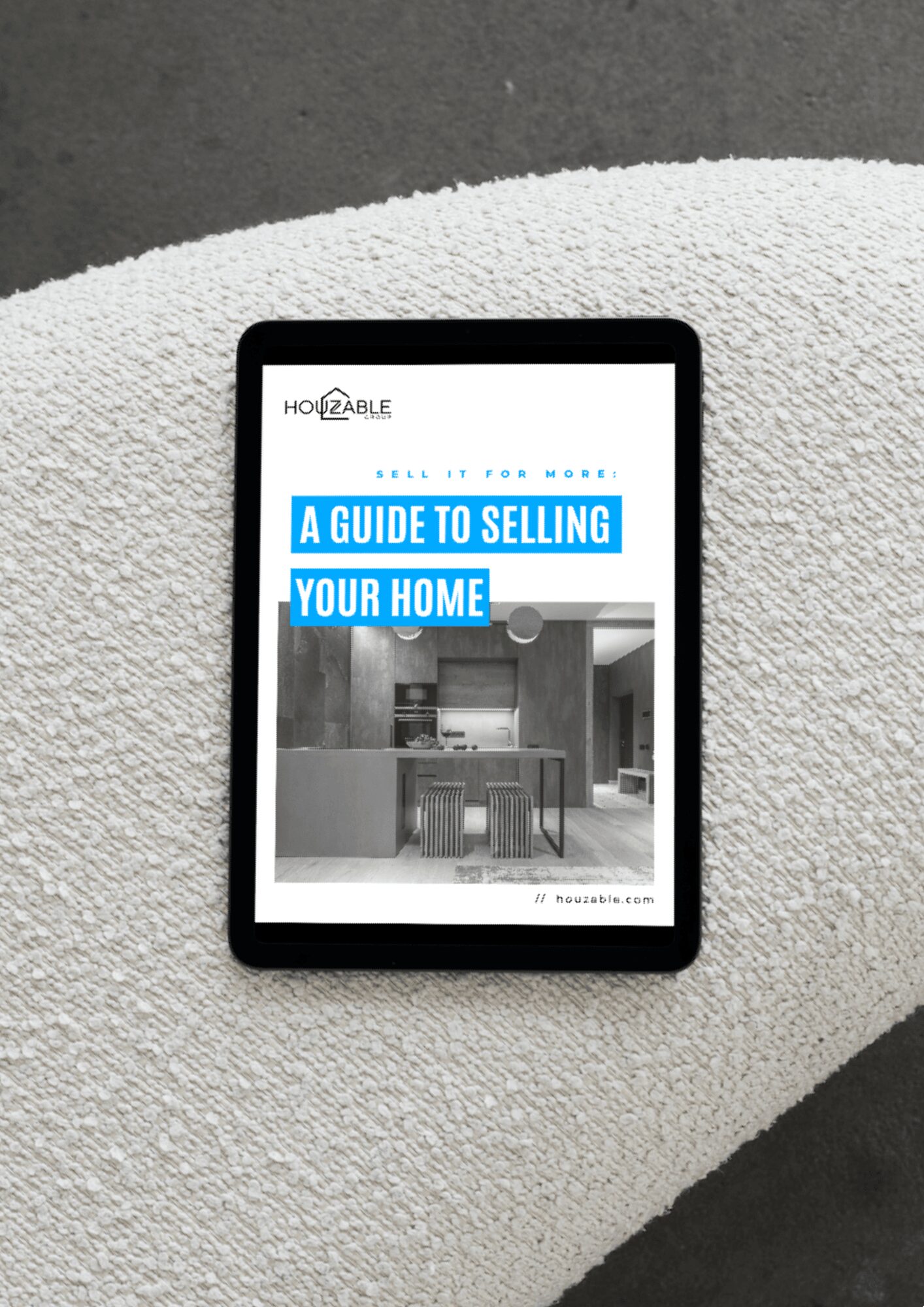 Tablet displaying a guide to selling homes, placed on a textured surface, with a modern interior image on the screen.