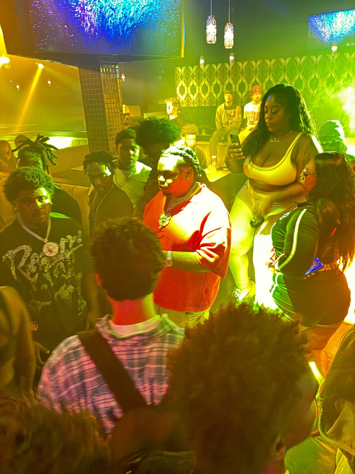 People dancing in a club with colorful lights and a lively atmosphere.