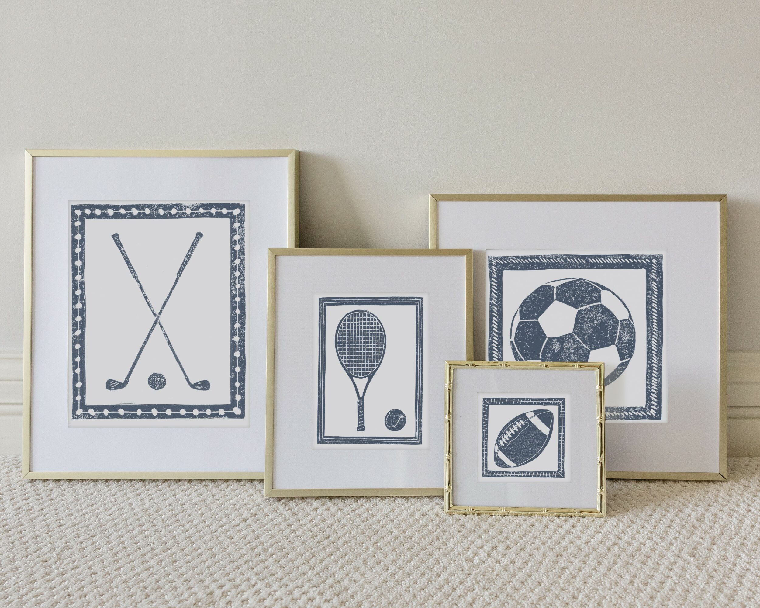 Five framed sports-themed pictures leaning against a wall, featuring hockey sticks, a tennis racket, a soccer ball, and a football.