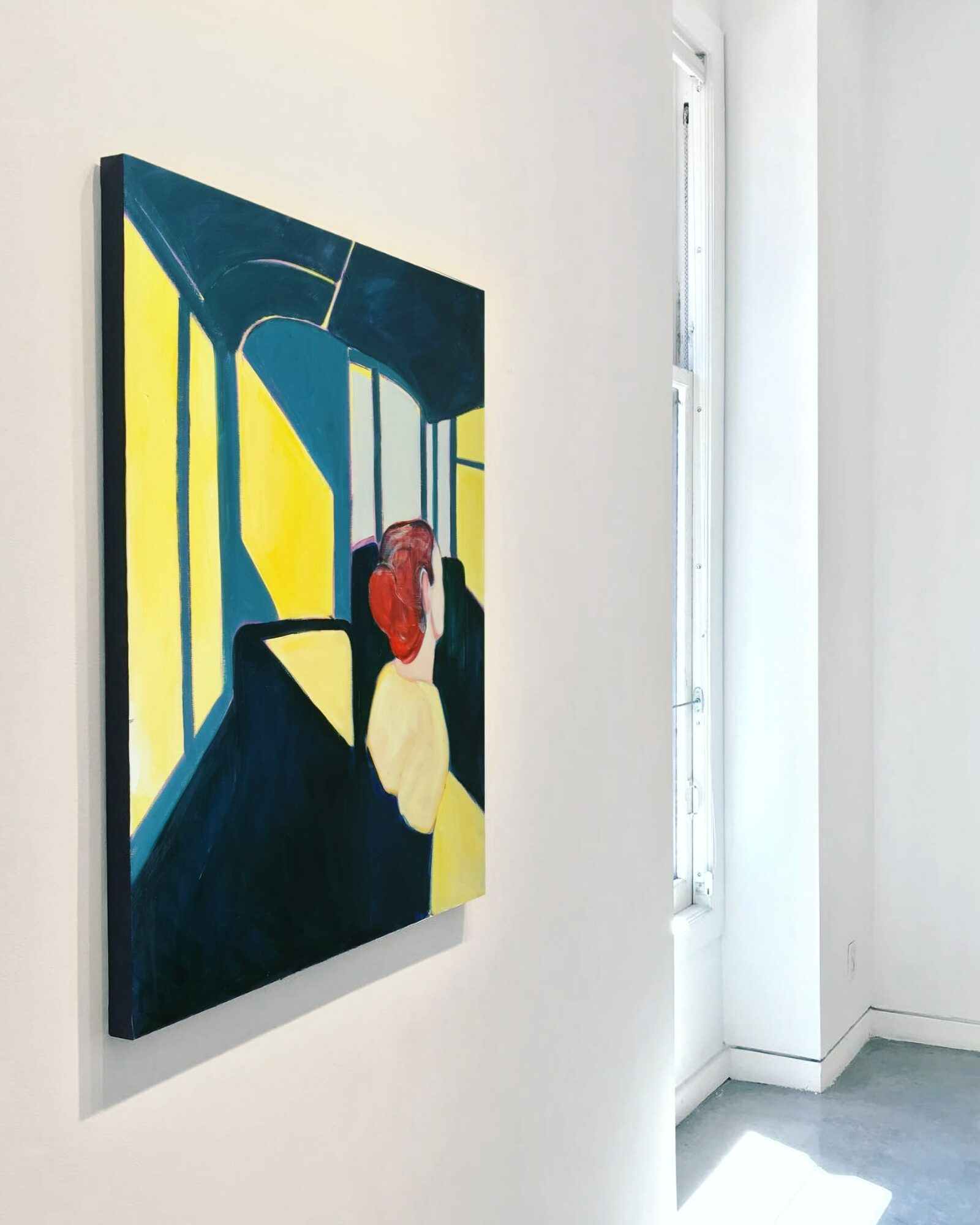 Abstract painting with bold yellow, blue, black, and red shapes on a white wall, next to a window.