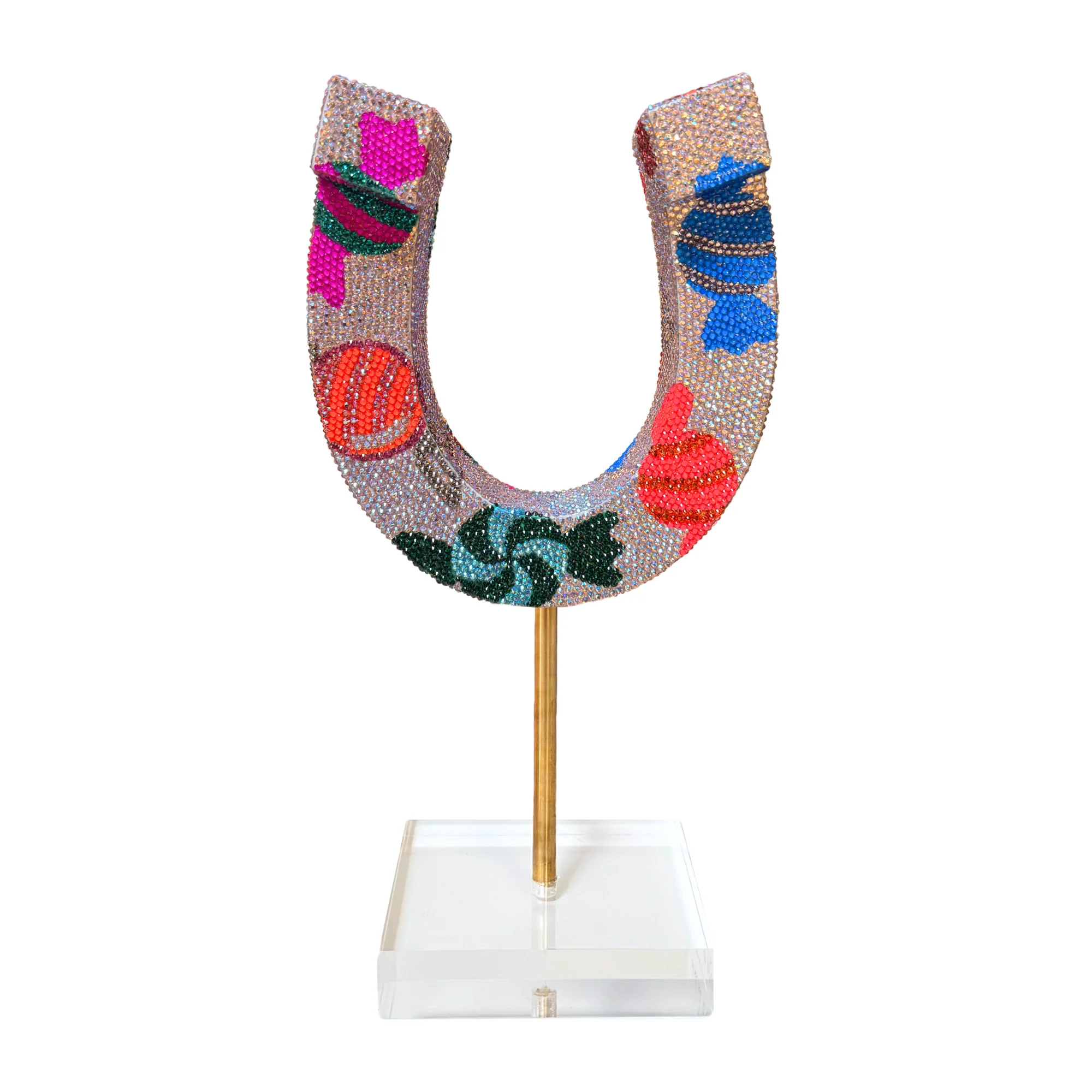 Decorative letter U with colorful patterns, mounted on a stick and displayed on a clear stand.