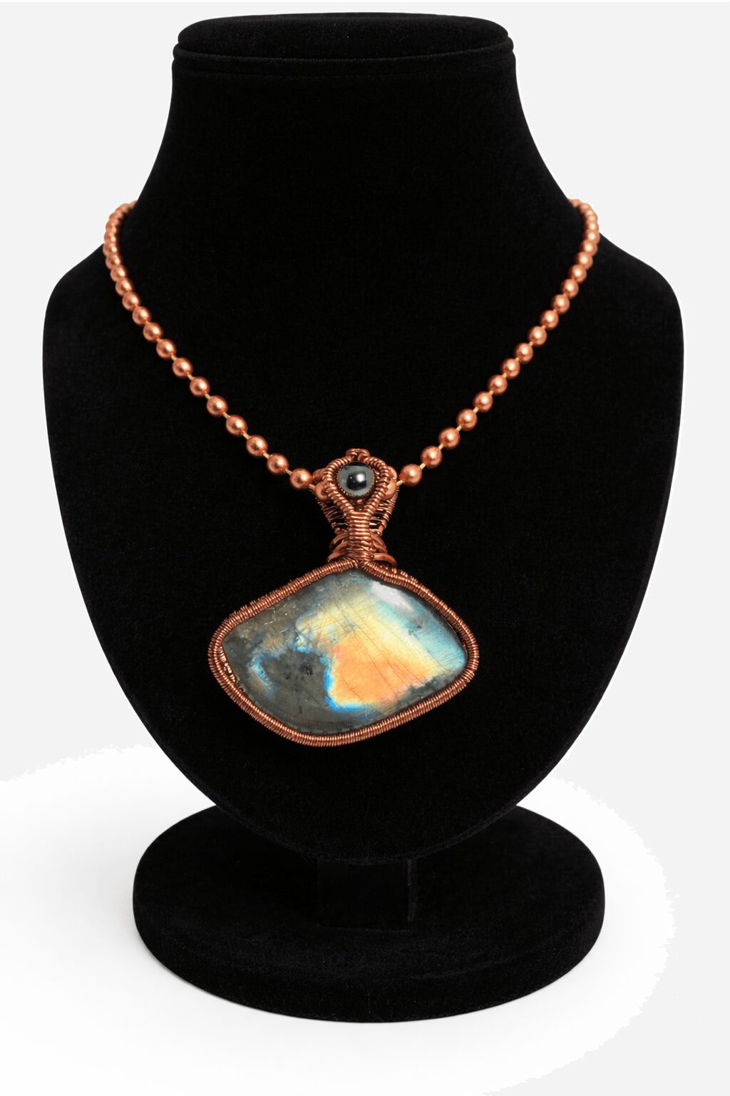 Necklace with a large, iridescent pendant on a black display bust.