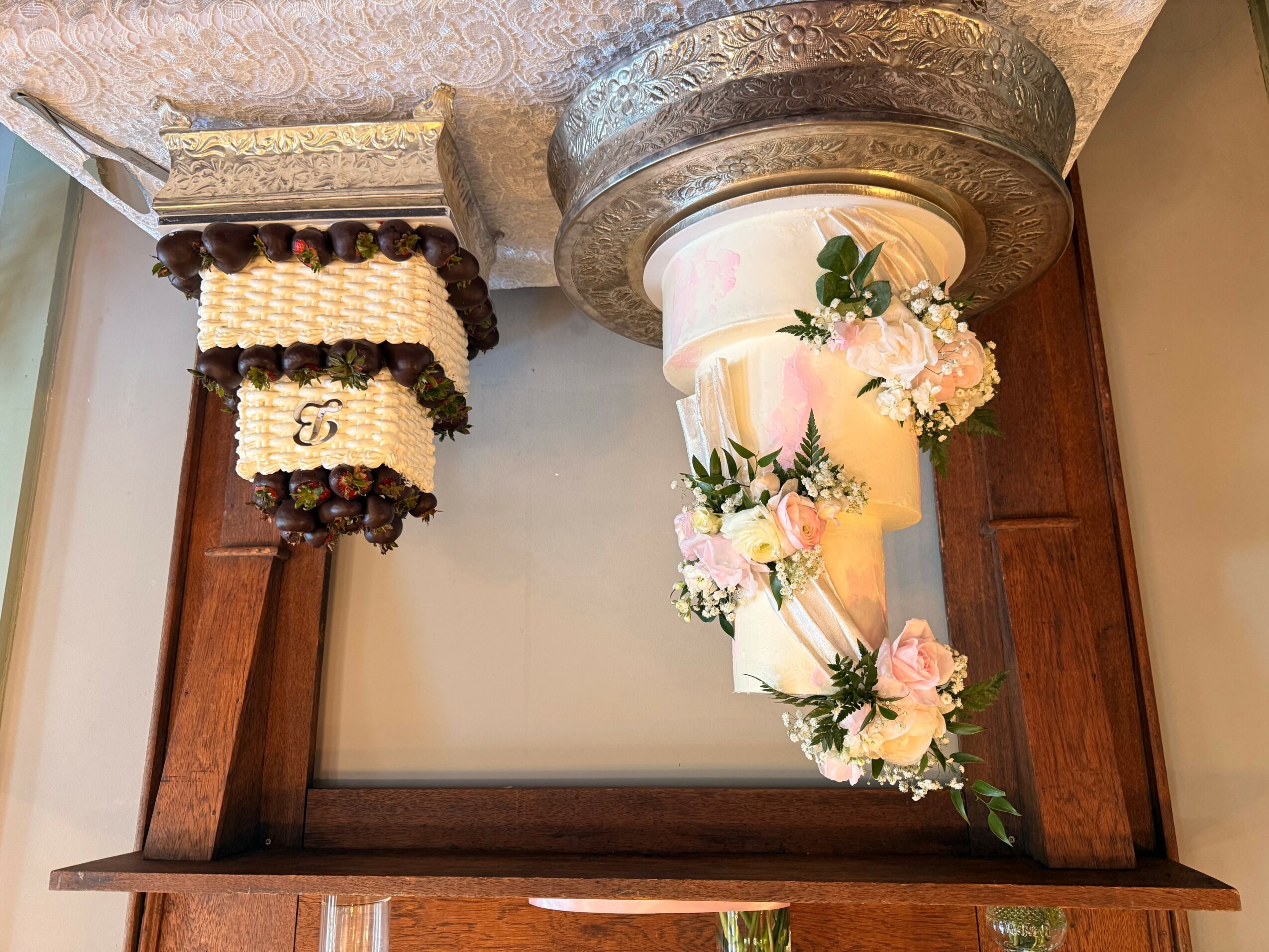 Upright table with a floral arrangement and a cake on a wooden table, viewed from the side.