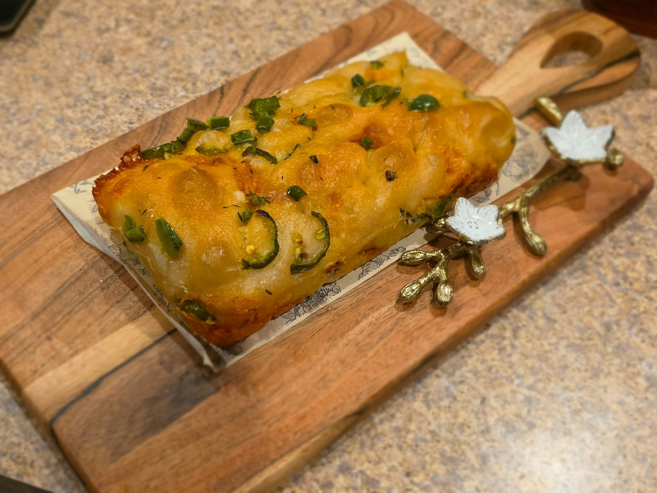 Baked dish with cheese and green herbs on a wooden serving board, viewed from above.