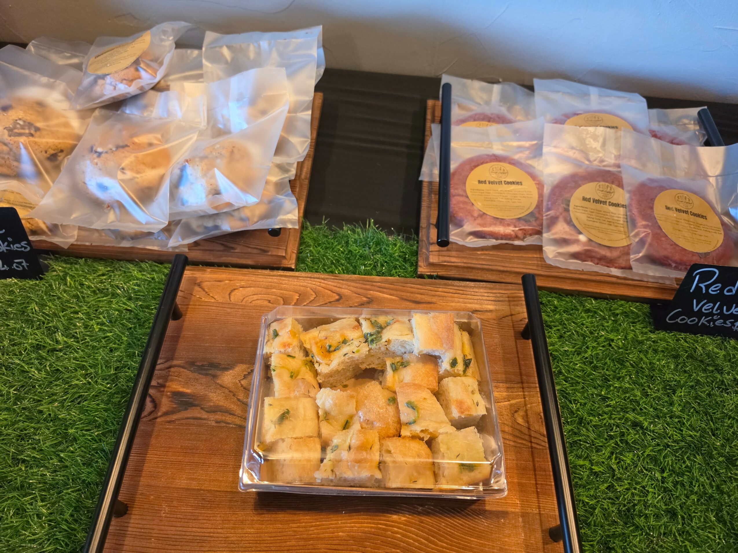 Tray of small, square, yellow and green food pieces on a wooden surface, with other food packages nearby.