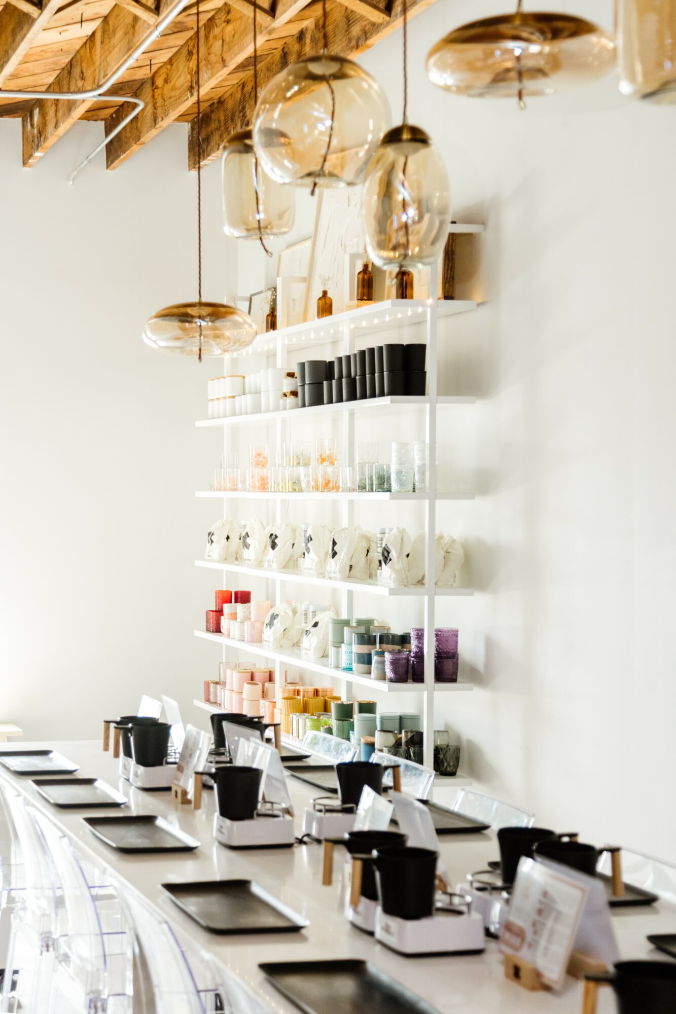 Display shelf with various products and hanging glass light fixtures in a modern interior.