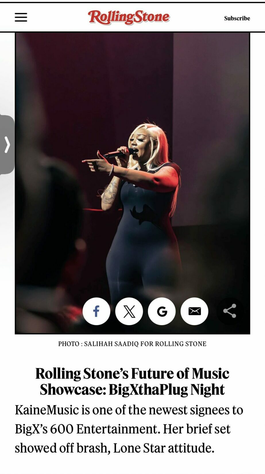 Performer on stage playing flute, with dark background and spotlight, wearing a dark outfit, side view, audience in foreground.