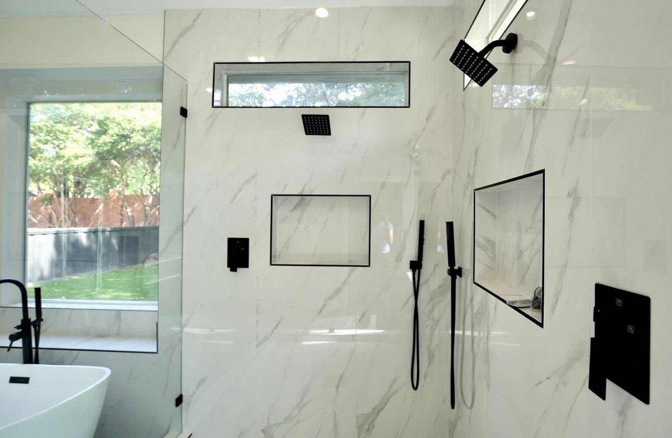 Modern bathroom with marble walls, shower area, window, and black fixtures.